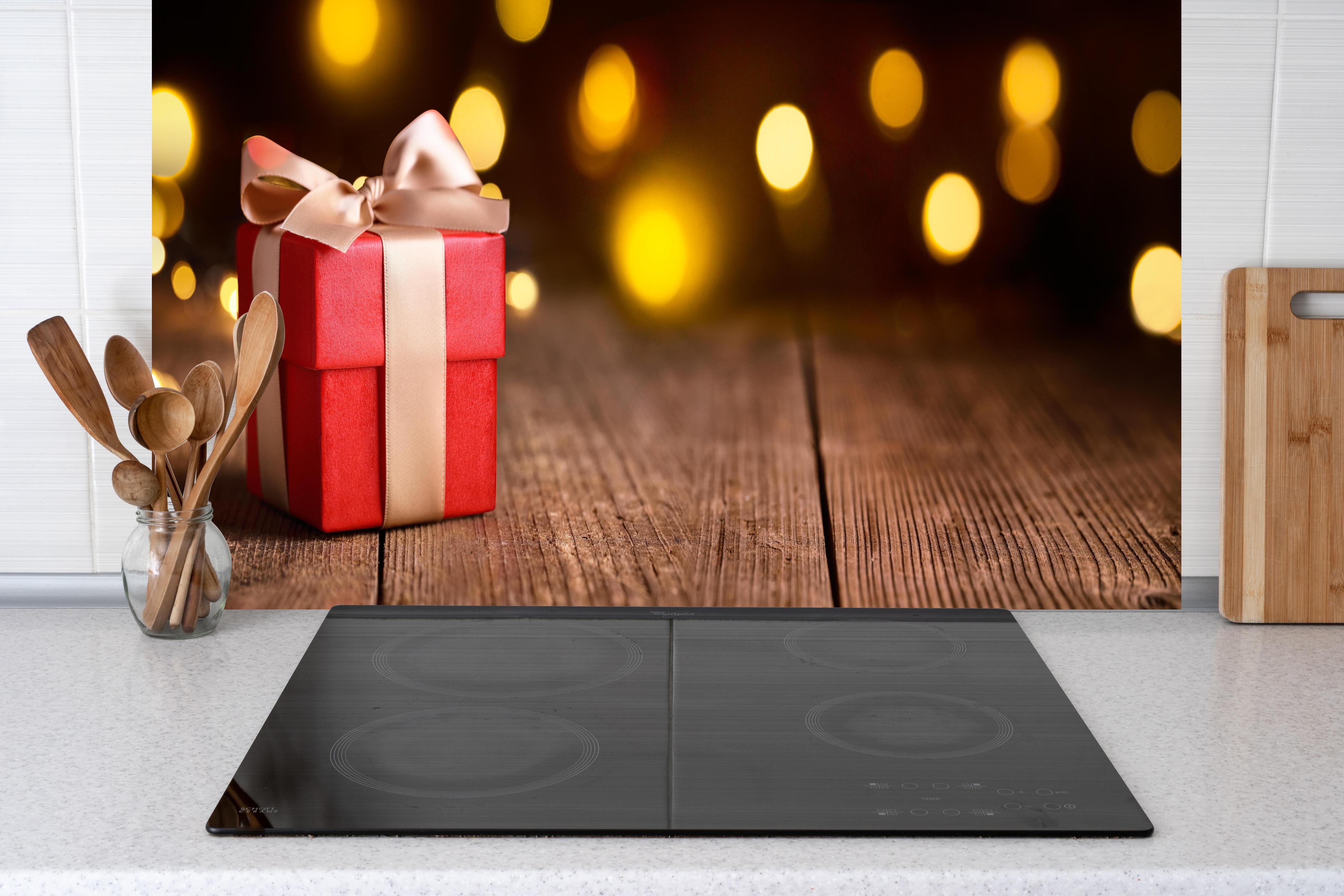 Küche - Weihnachtsgeschenk auf festlichem Hintergrund hinter weißen Hochglanz-Küchenregalen und schwarzem Wasserhahn