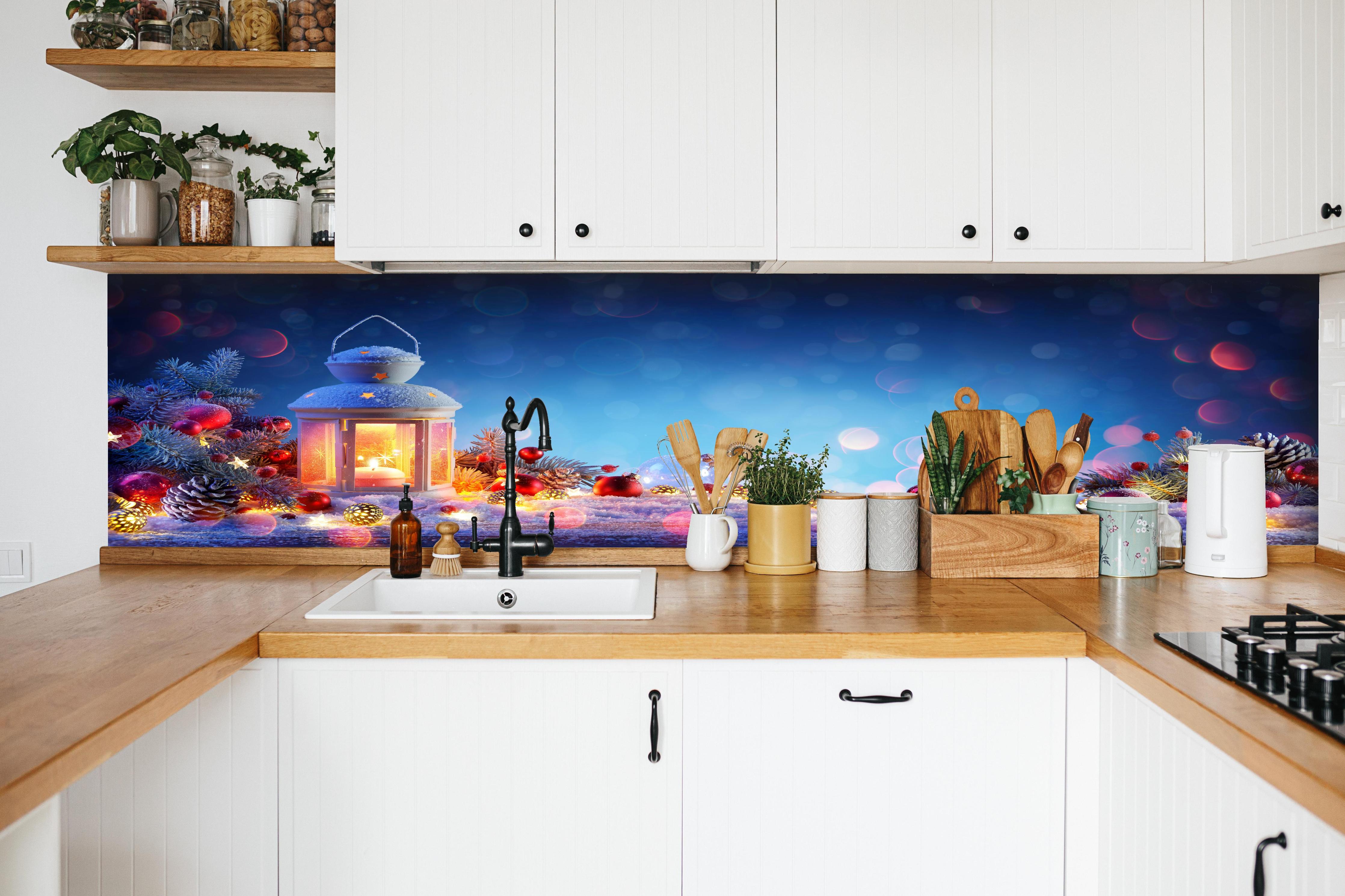 Küche - Weihnachtslaterne auf verschneiten Tisch hinter weißen Hochglanz-Küchenregalen und schwarzem Wasserhahn