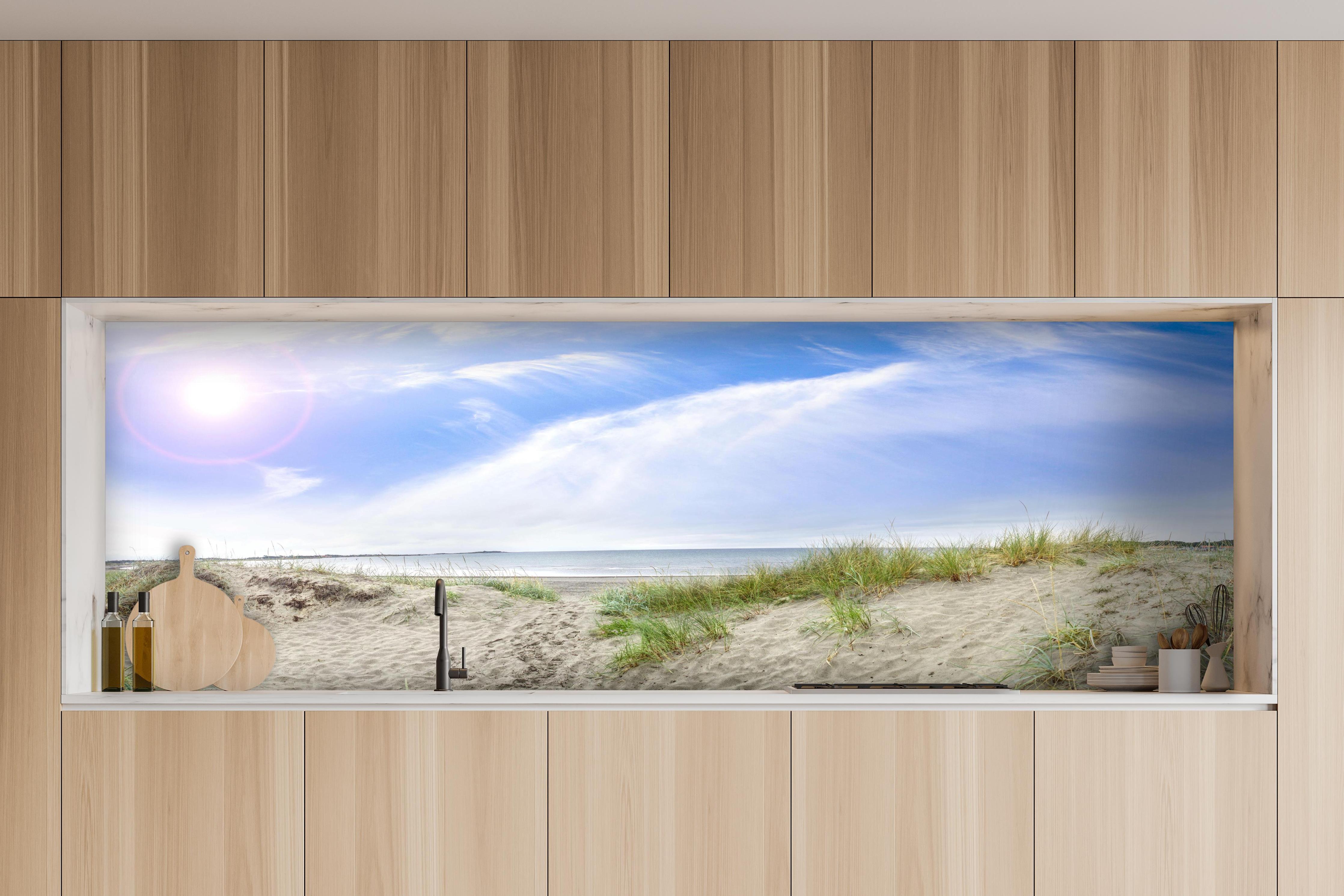 Küche - Weitläufige Strandlandschaft mit sanften Dünen, Himmel und ruhigem Wasser hinter weißen Hochglanz-Küchenregalen und schwarzem Wasserhahn