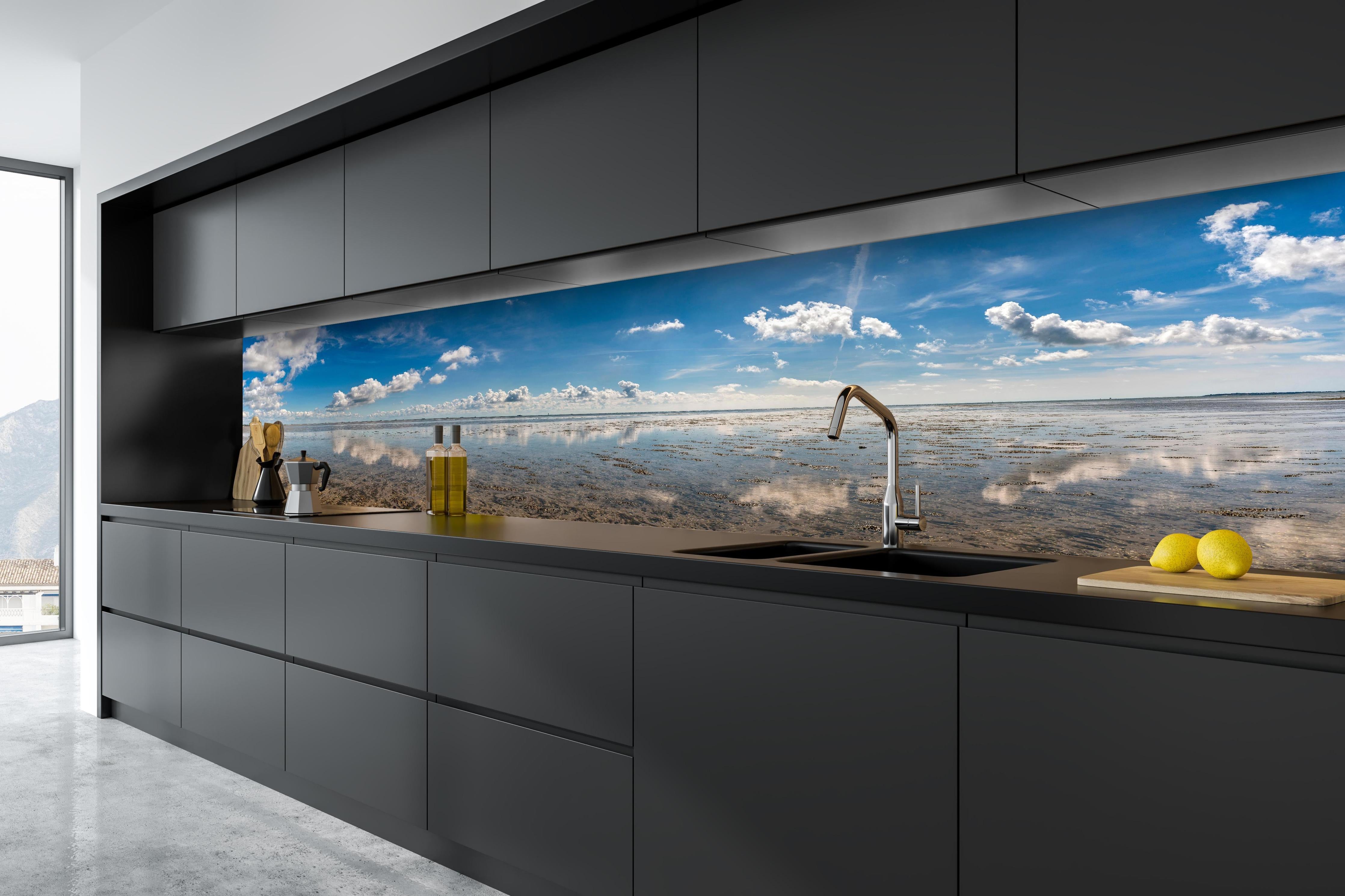 Küche - Weitläufiger Himmel und spiegelnde Wasseroberfläche mit Wolkenreflexionen hinter weißen Hochglanz-Küchenregalen und schwarzem Wasserhahn