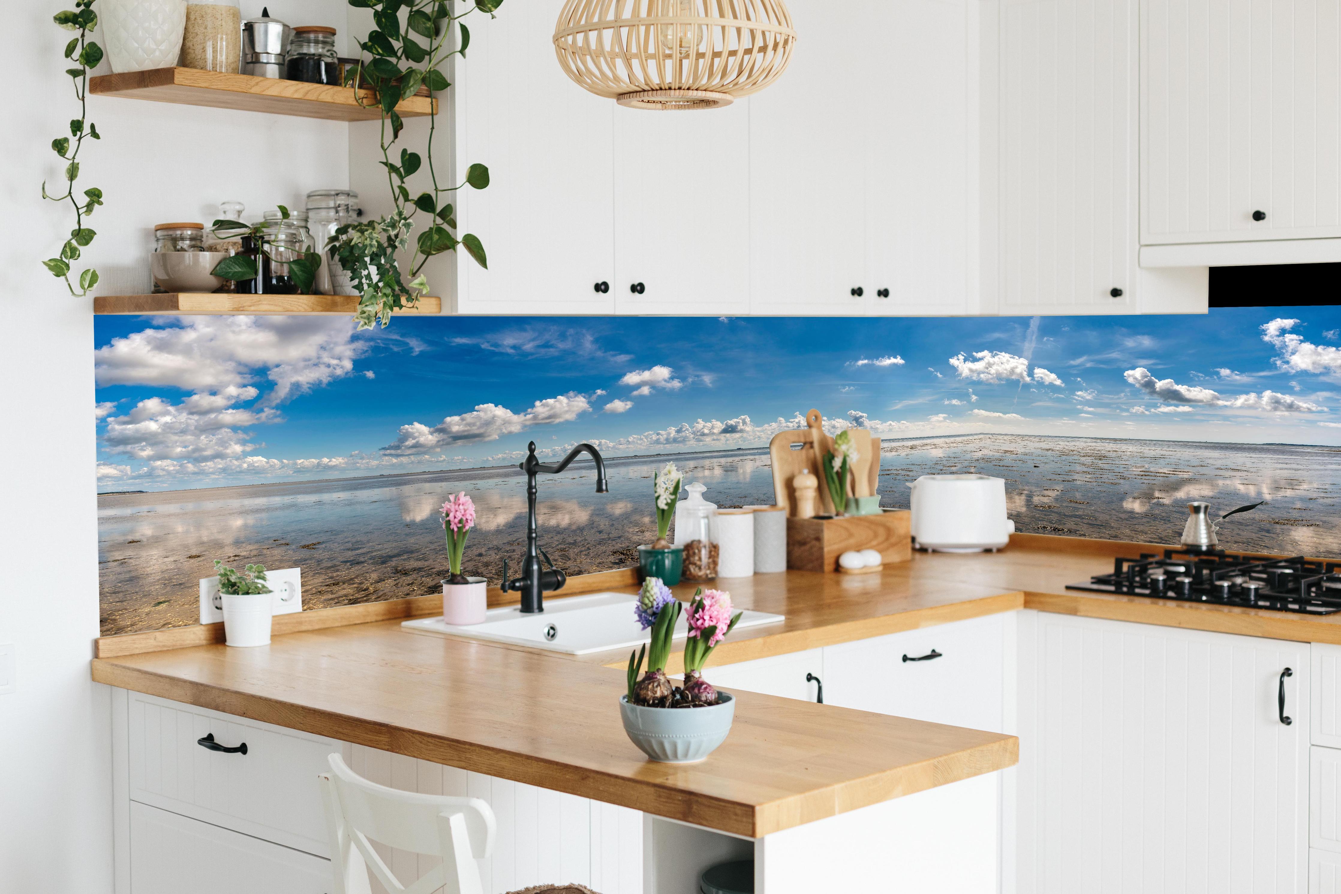 Küche - Weitläufiger Himmel und spiegelnde Wasseroberfläche mit Wolkenreflexionen hinter weißen Hochglanz-Küchenregalen und schwarzem Wasserhahn