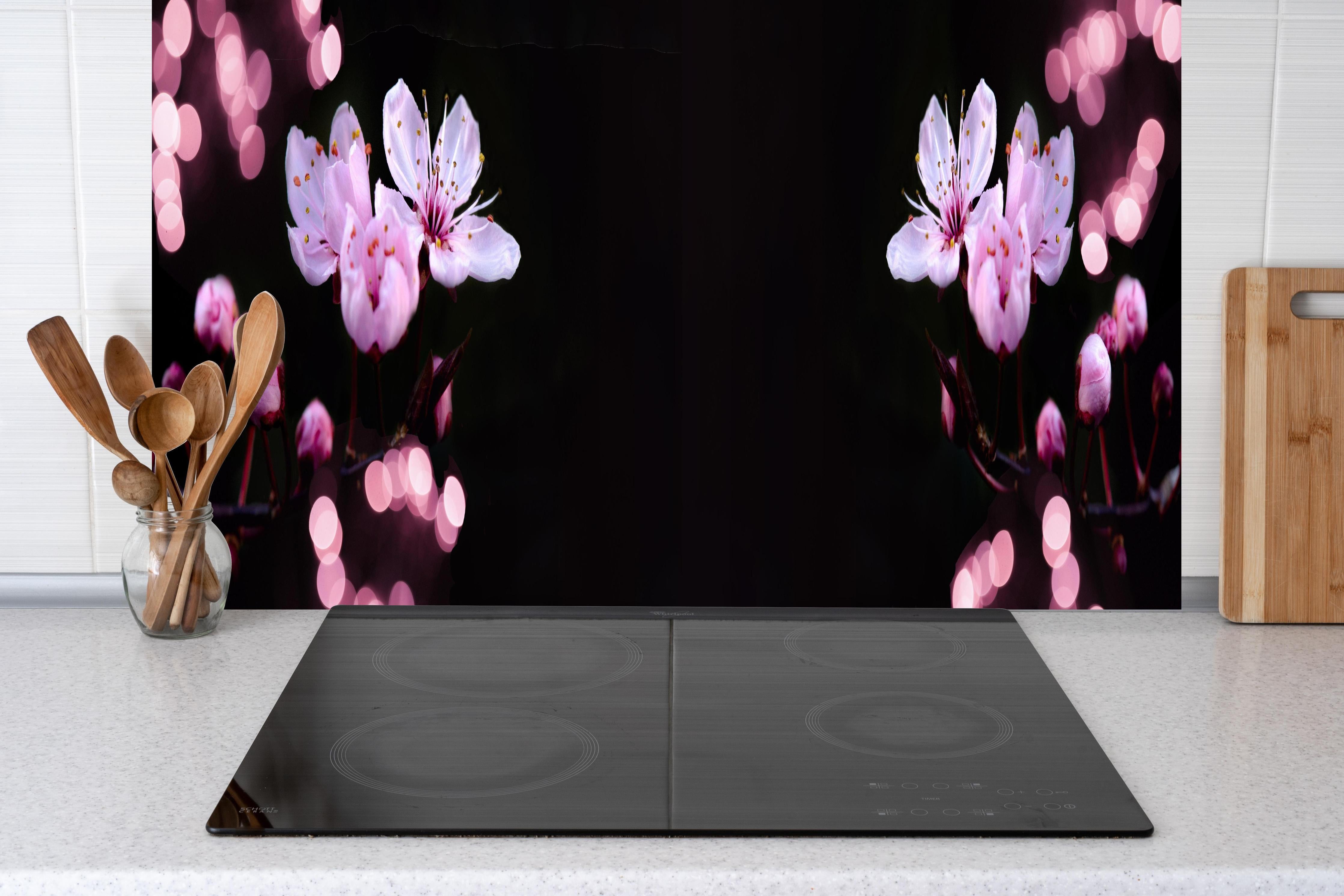 Küche - Zarte Rosa Kirschblüten beleuchtet in Dunkelheit hinter weißen Hochglanz-Küchenregalen und schwarzem Wasserhahn