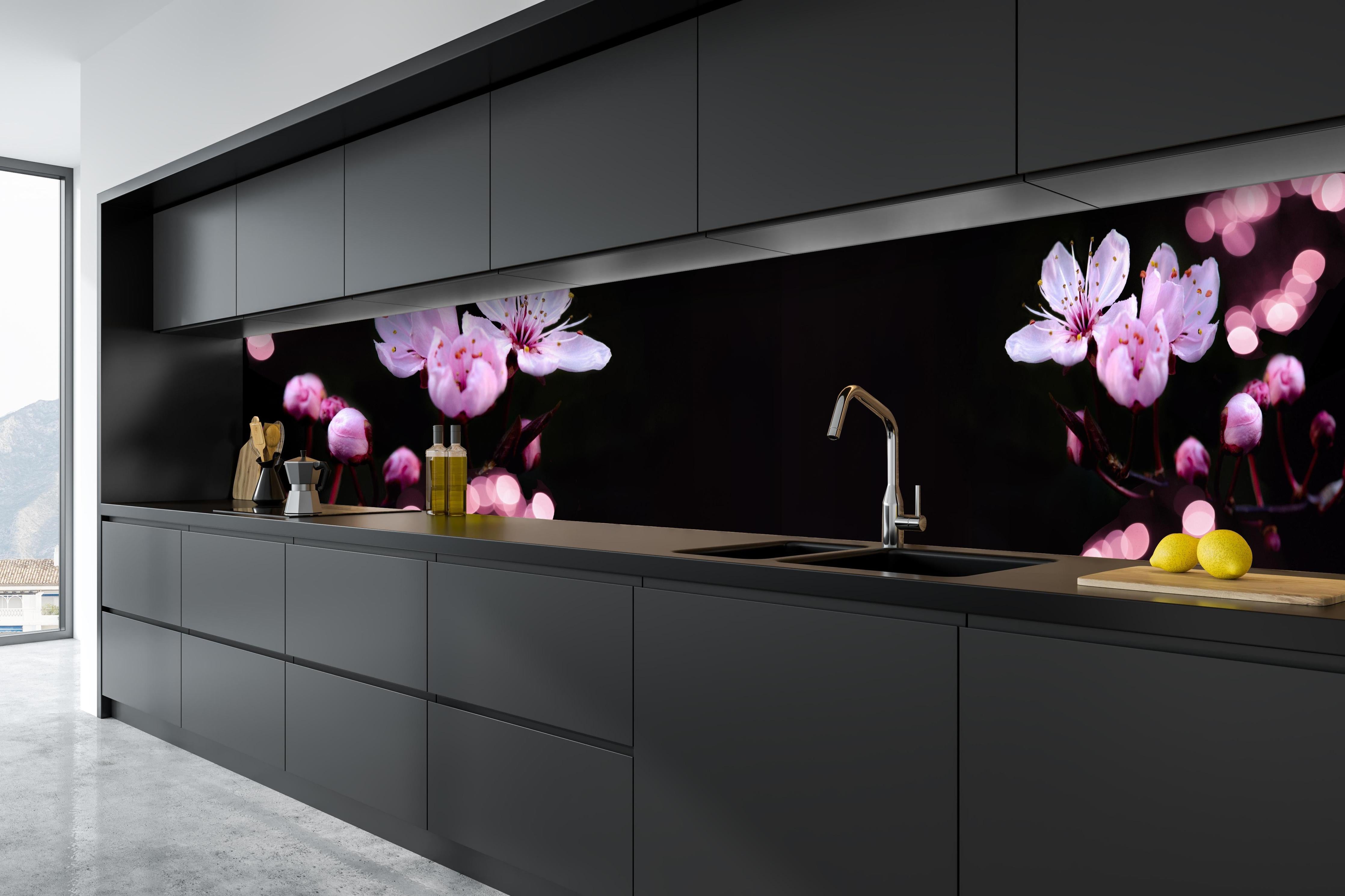 Küche - Zarte Rosa Kirschblüten beleuchtet in Dunkelheit hinter weißen Hochglanz-Küchenregalen und schwarzem Wasserhahn
