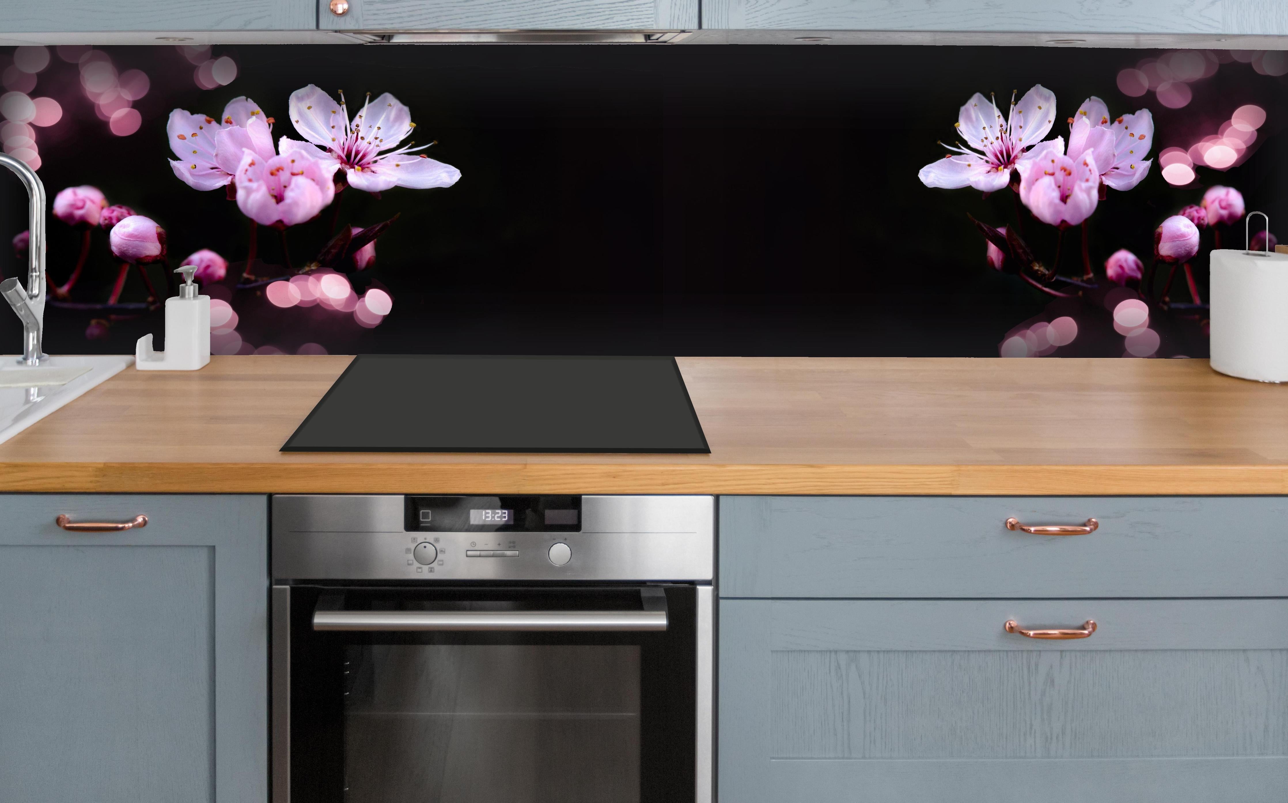 Küche - Zarte Rosa Kirschblüten beleuchtet in Dunkelheit hinter weißen Hochglanz-Küchenregalen und schwarzem Wasserhahn