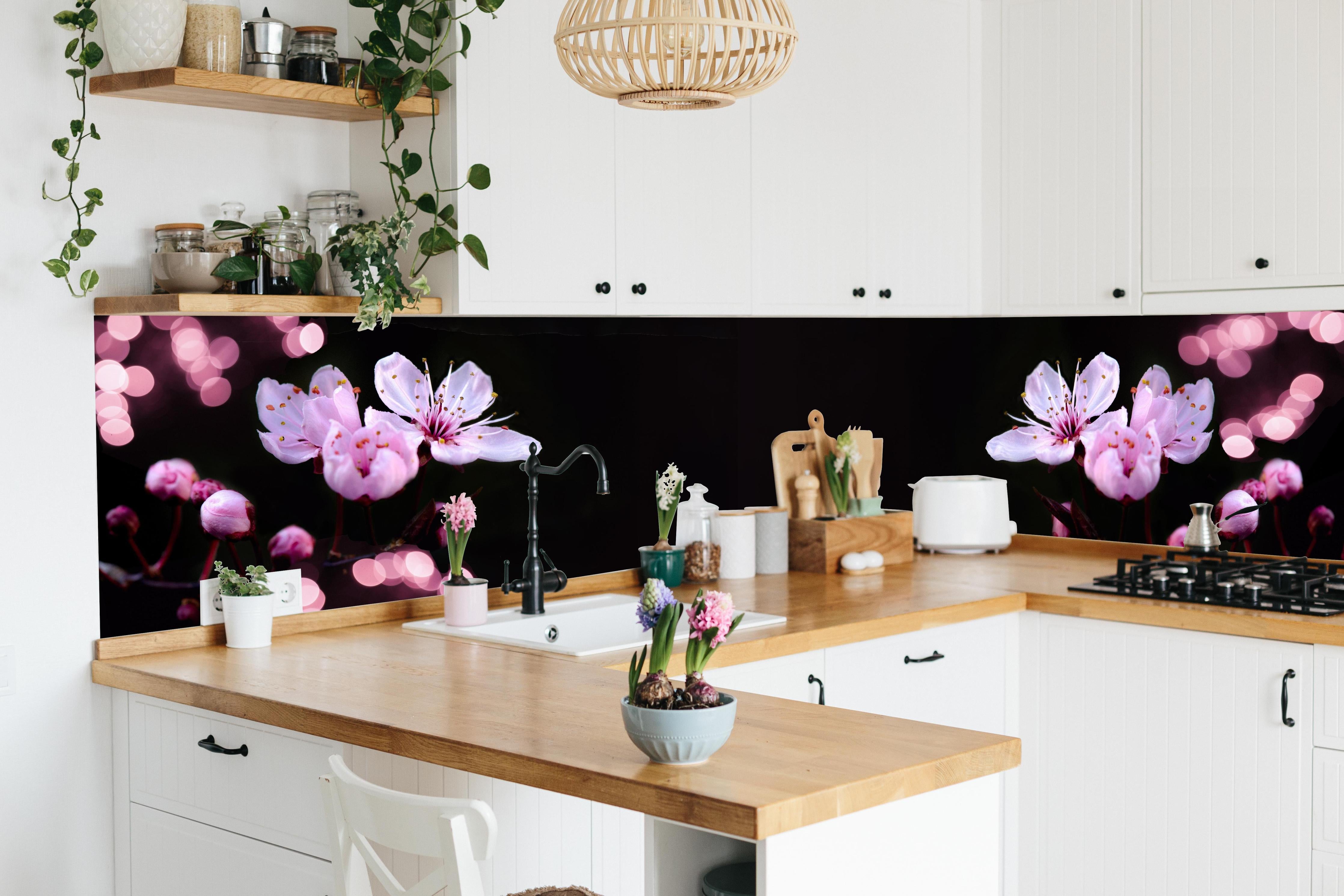 Küche - Zarte Rosa Kirschblüten beleuchtet in Dunkelheit hinter weißen Hochglanz-Küchenregalen und schwarzem Wasserhahn