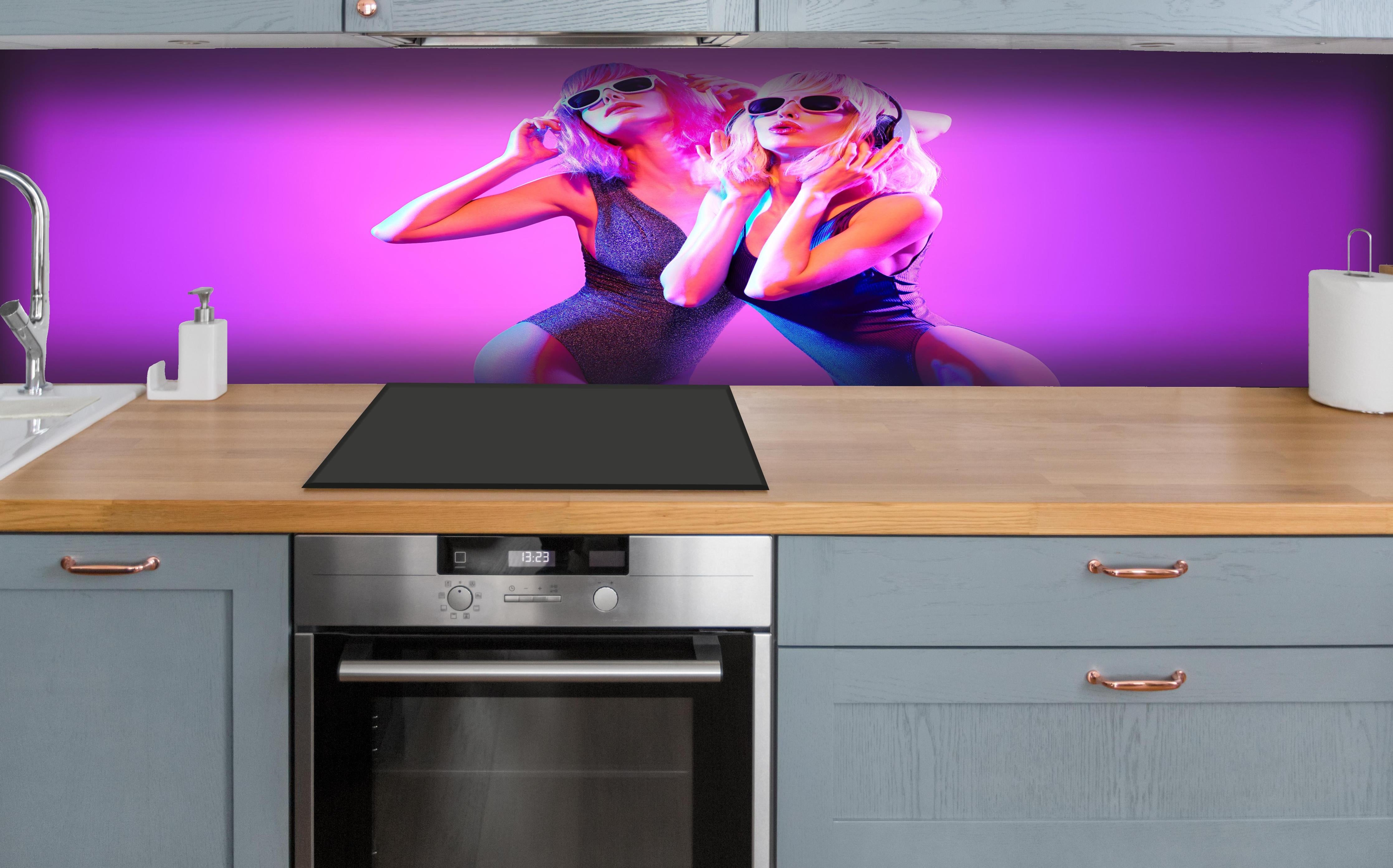 Küche - Zwei DJ Fitness Frau in bunten Neonlicht. Disco hinter weißen Hochglanz-Küchenregalen und schwarzem Wasserhahn