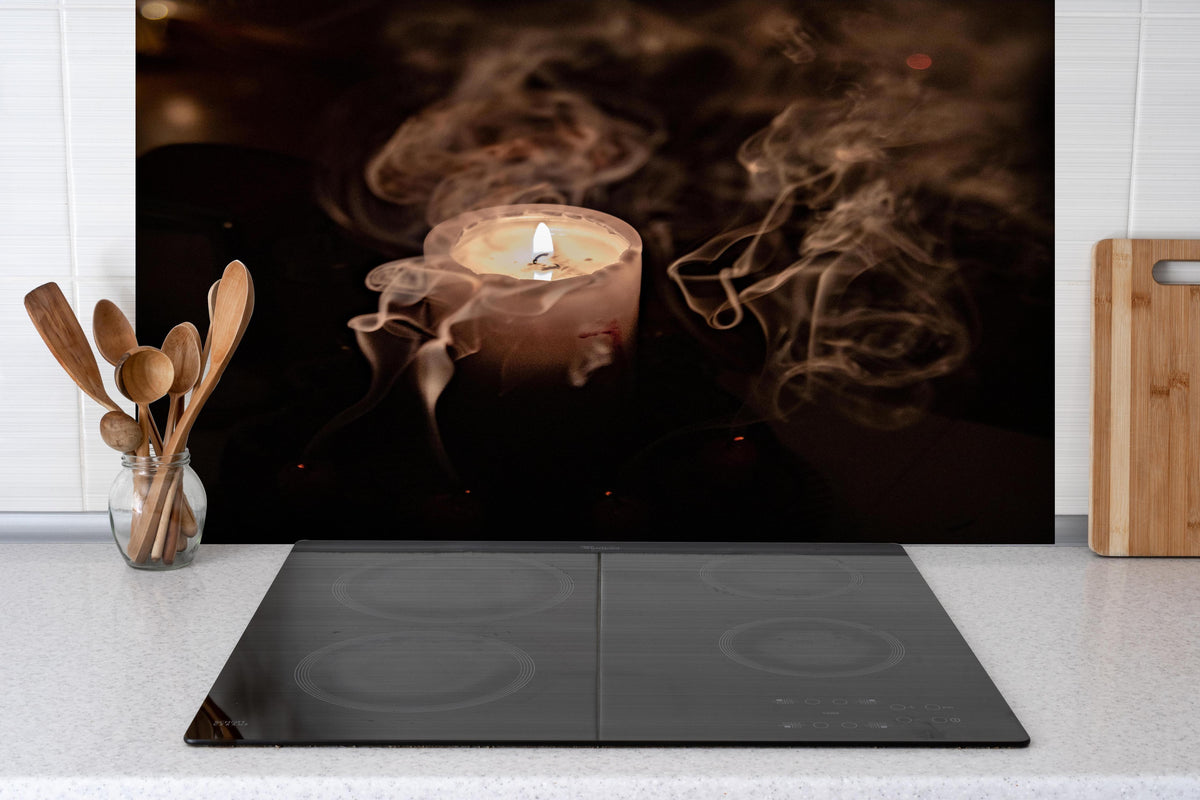 Spritzschutz -  Mystischer Kerzenrauch bei brennender Kerze hinter einem Cerankochfeld zwischen Holz-Kochutensilien
