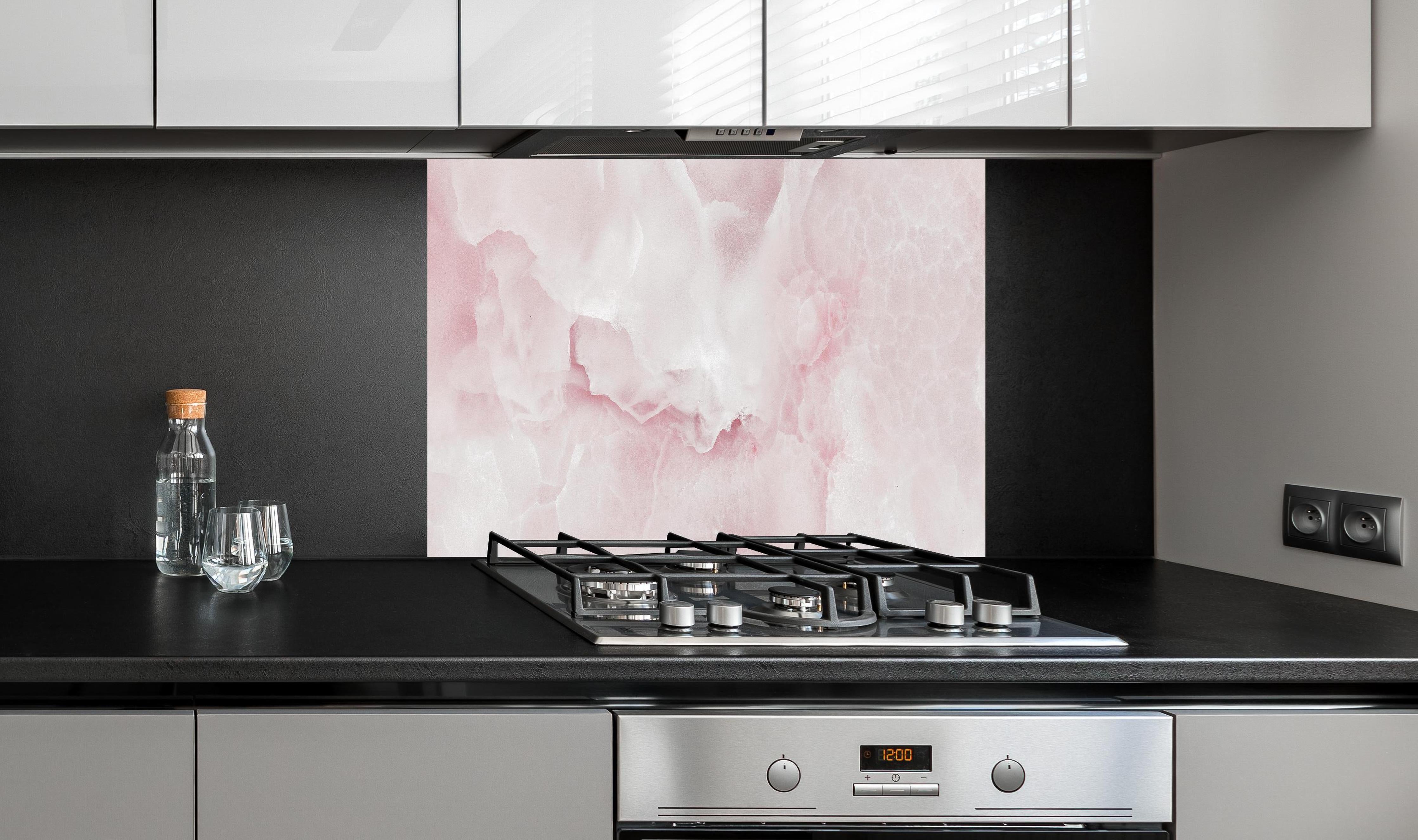 Spritzschutz -  Rosa Emperador Onyx Marmor hinter einem Cerankochfeld zwischen Holz-Kochutensilien
