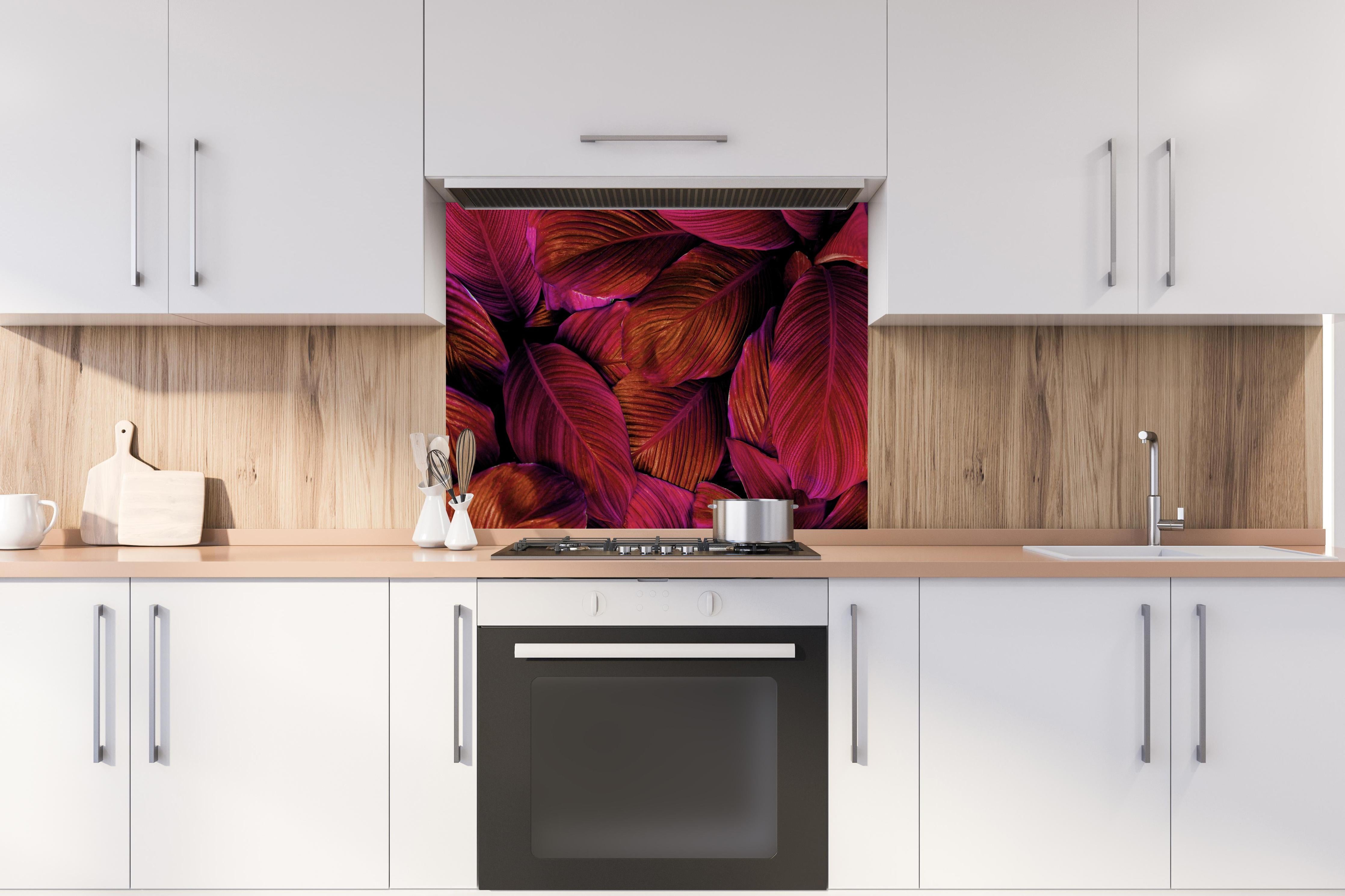 Spritzschutz -  Spathiphyllum cannifolium - Rosa Blätter hinter einem Cerankochfeld zwischen Holz-Kochutensilien
