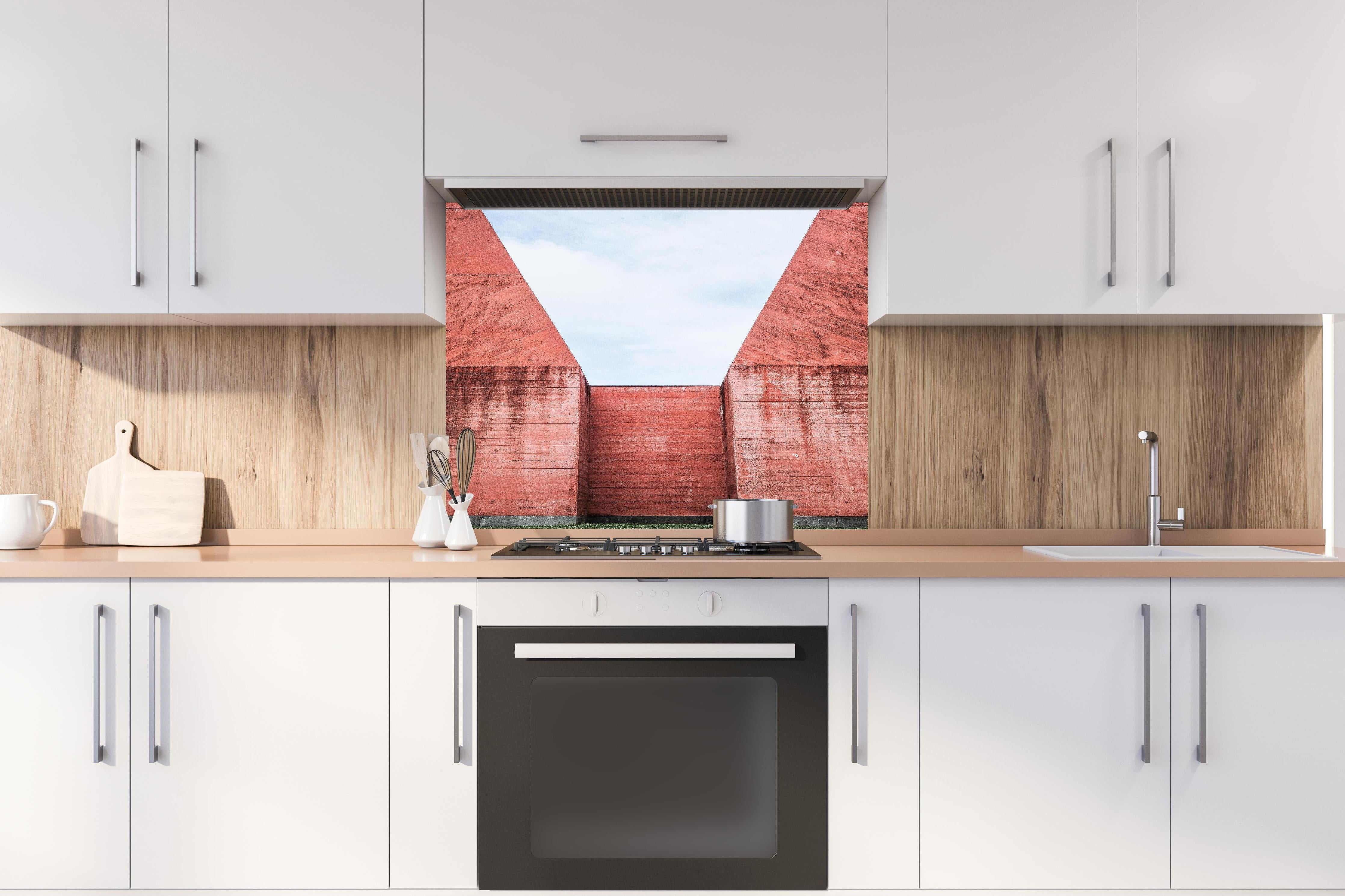 Spritzschutz - Abstrakte Architektur in Marsrot hinter einem Cerankochfeld zwischen Holz-Kochutensilien
