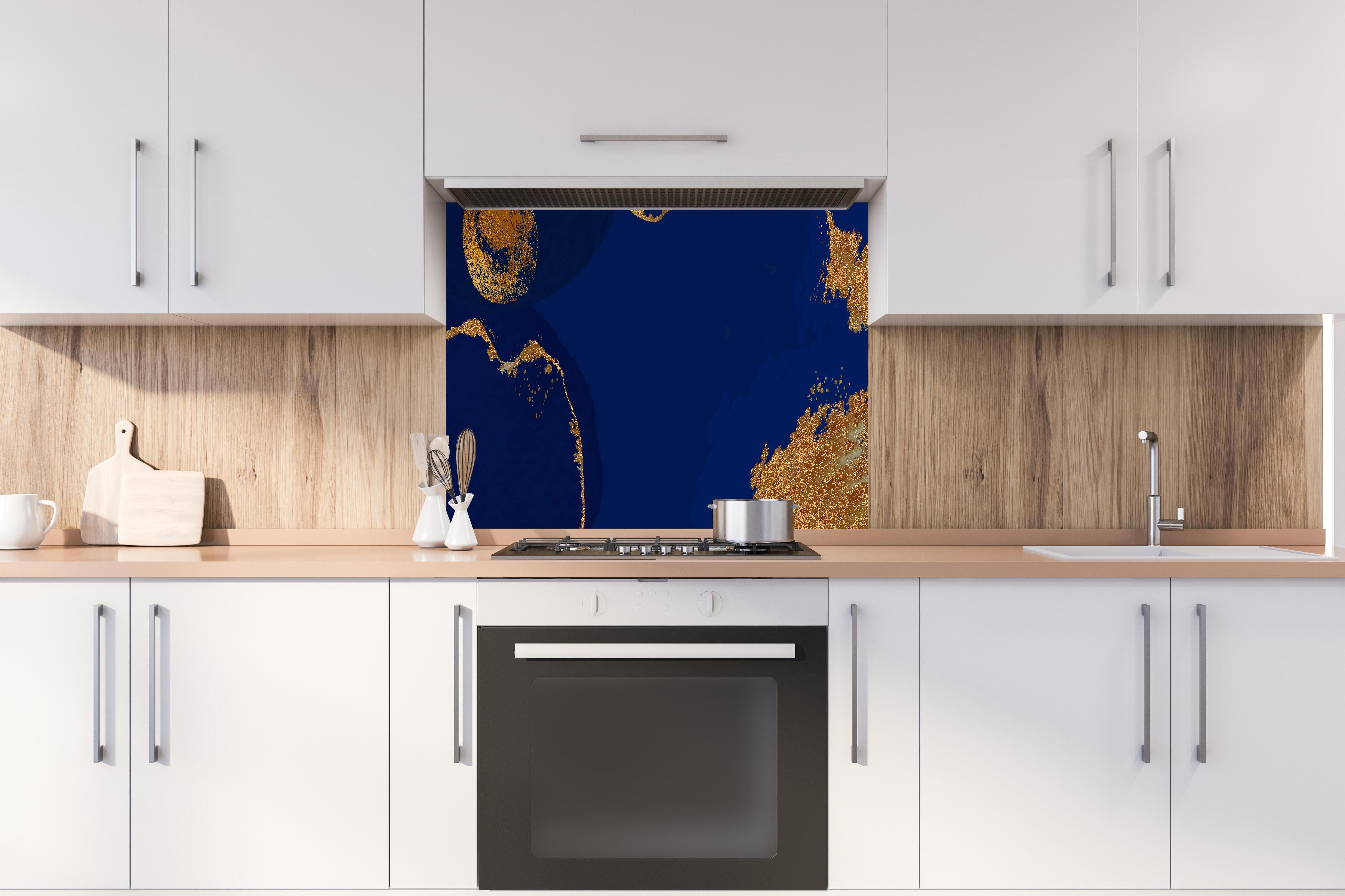 Spritzschutz - Abstrakte Kunst in Gold-und Blautönen hinter einem Cerankochfeld zwischen Holz-Kochutensilien
