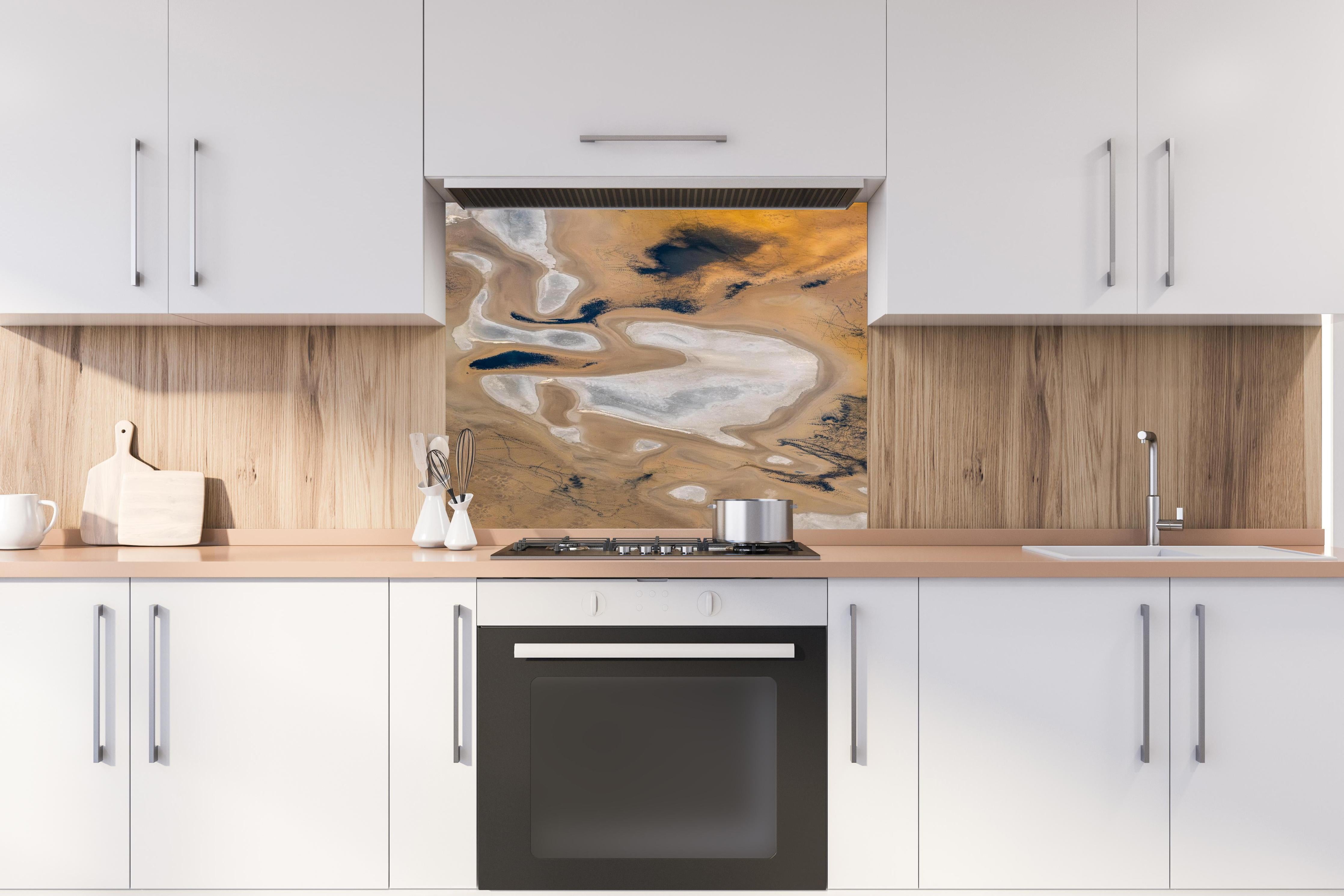 Spritzschutz - Abstrakte Landschaft in Beige-Tönen hinter einem Cerankochfeld zwischen Holz-Kochutensilien
