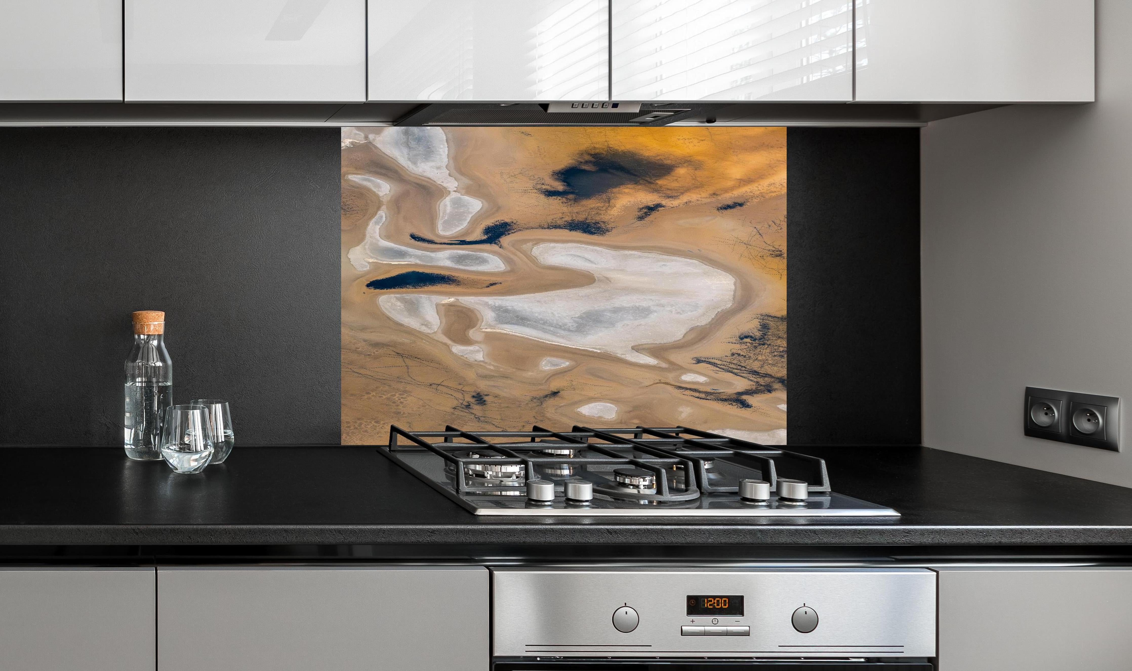Spritzschutz - Abstrakte Landschaft in Beige-Tönen hinter einem Cerankochfeld zwischen Holz-Kochutensilien

