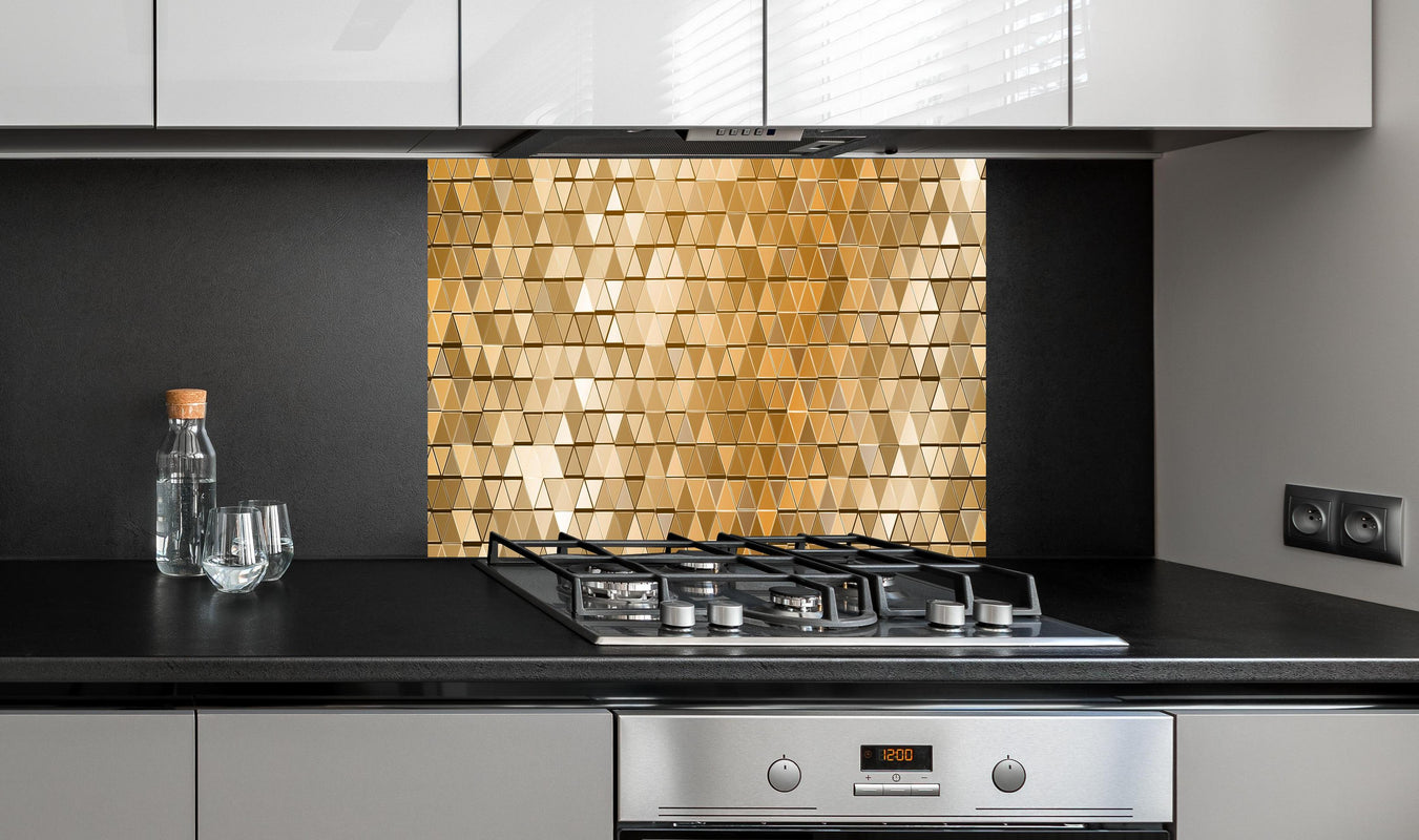 Spritzschutz - Abstrakte goldene Mosaik Wandverkleidung hinter einem Cerankochfeld zwischen Holz-Kochutensilien
