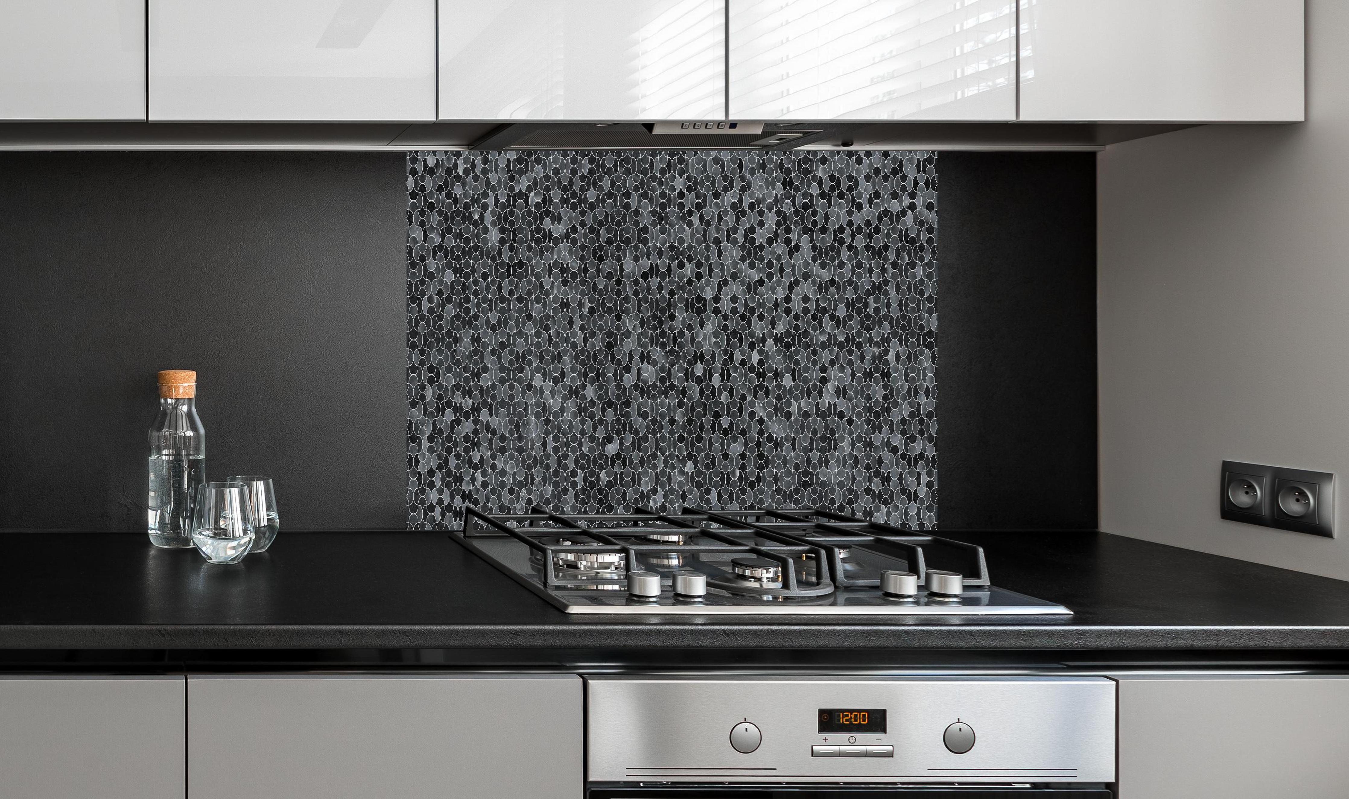 Spritzschutz - Abstrakte schwarze Pixel Mosaik Textur hinter einem Cerankochfeld zwischen Holz-Kochutensilien
