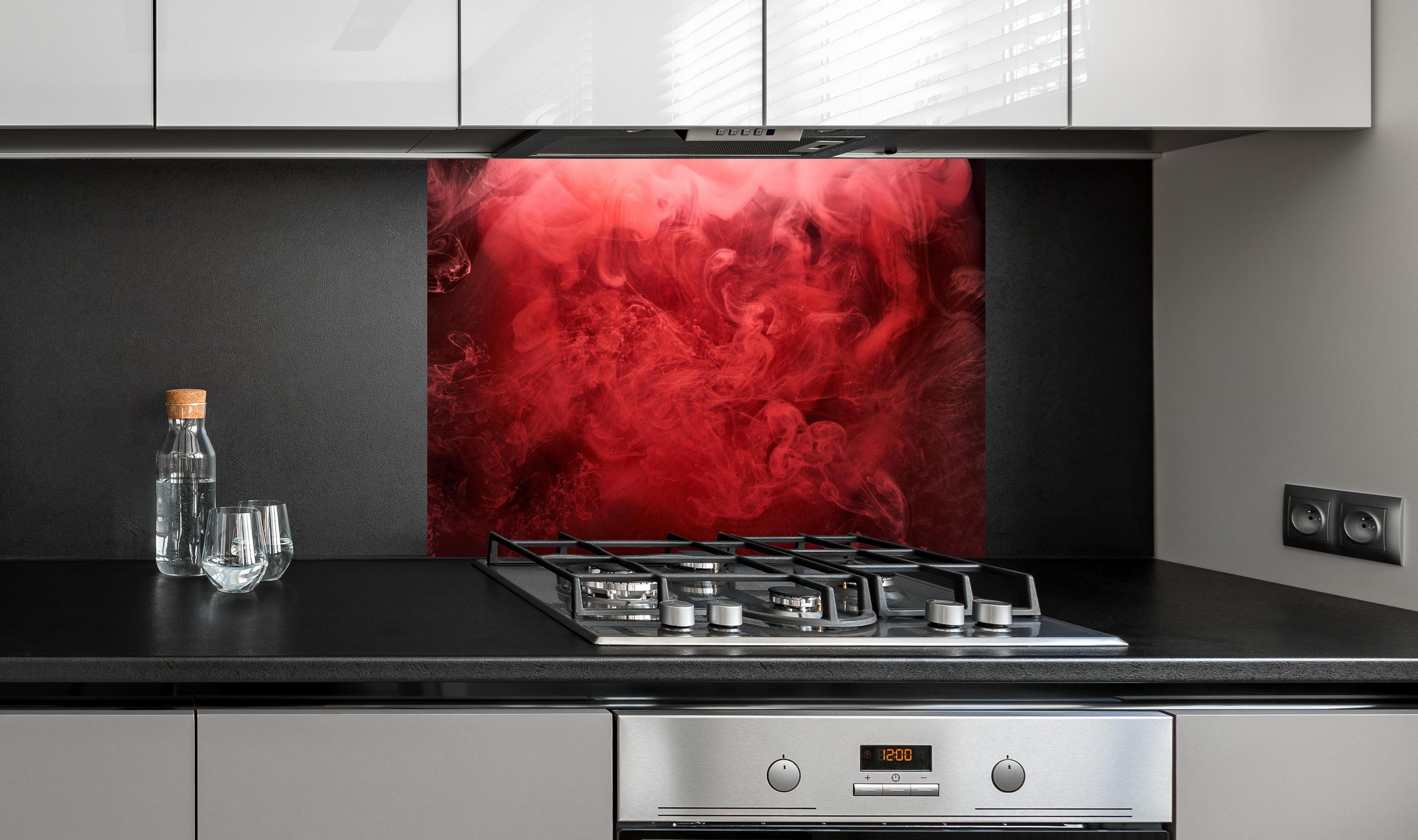 Spritzschutz - Abstrakter roter Ozean hinter einem Cerankochfeld zwischen Holz-Kochutensilien
