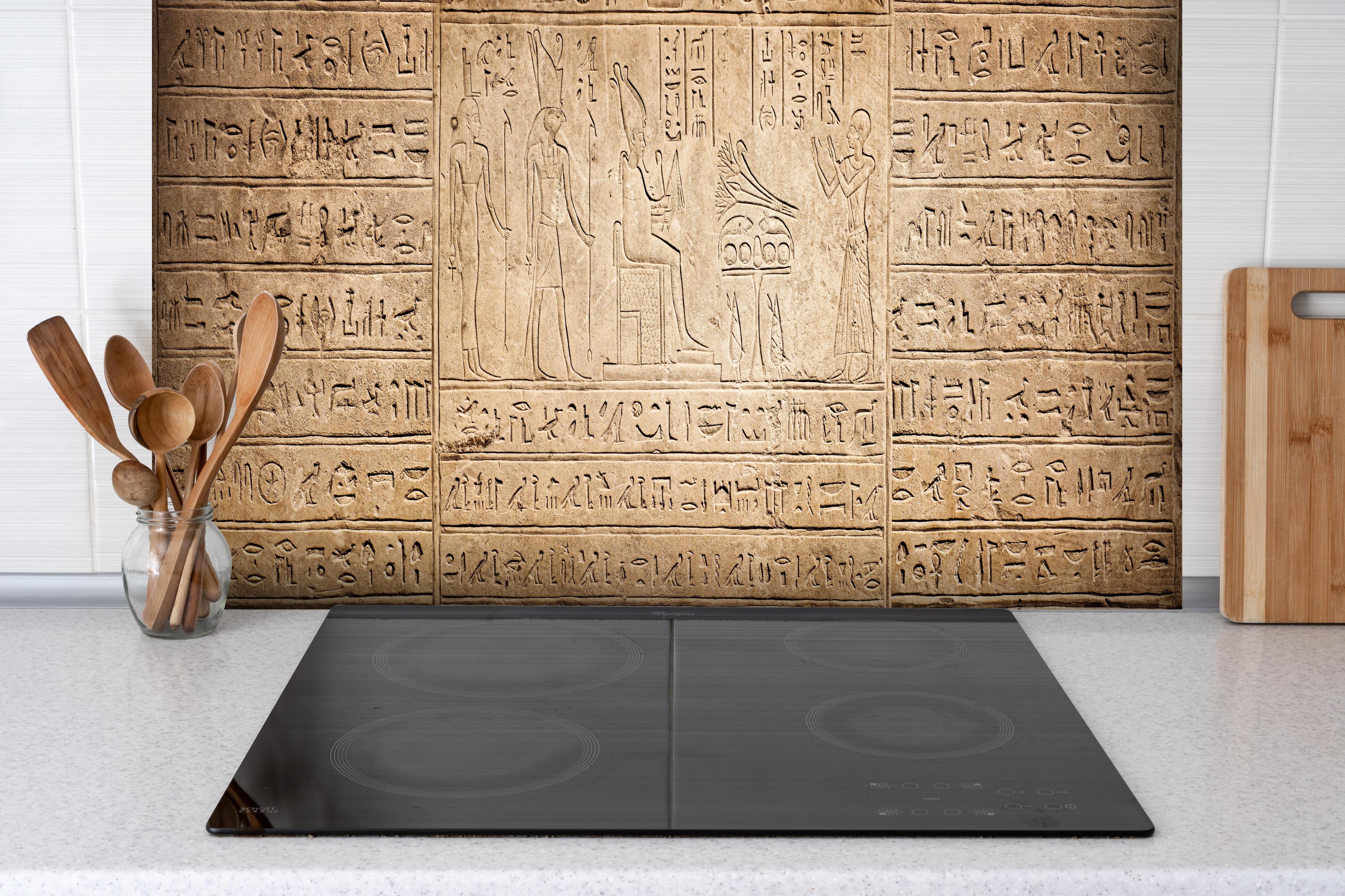 Spritzschutz - Ägyptische Hieroglyphen auf Sandstein hinter einem Cerankochfeld zwischen Holz-Kochutensilien
