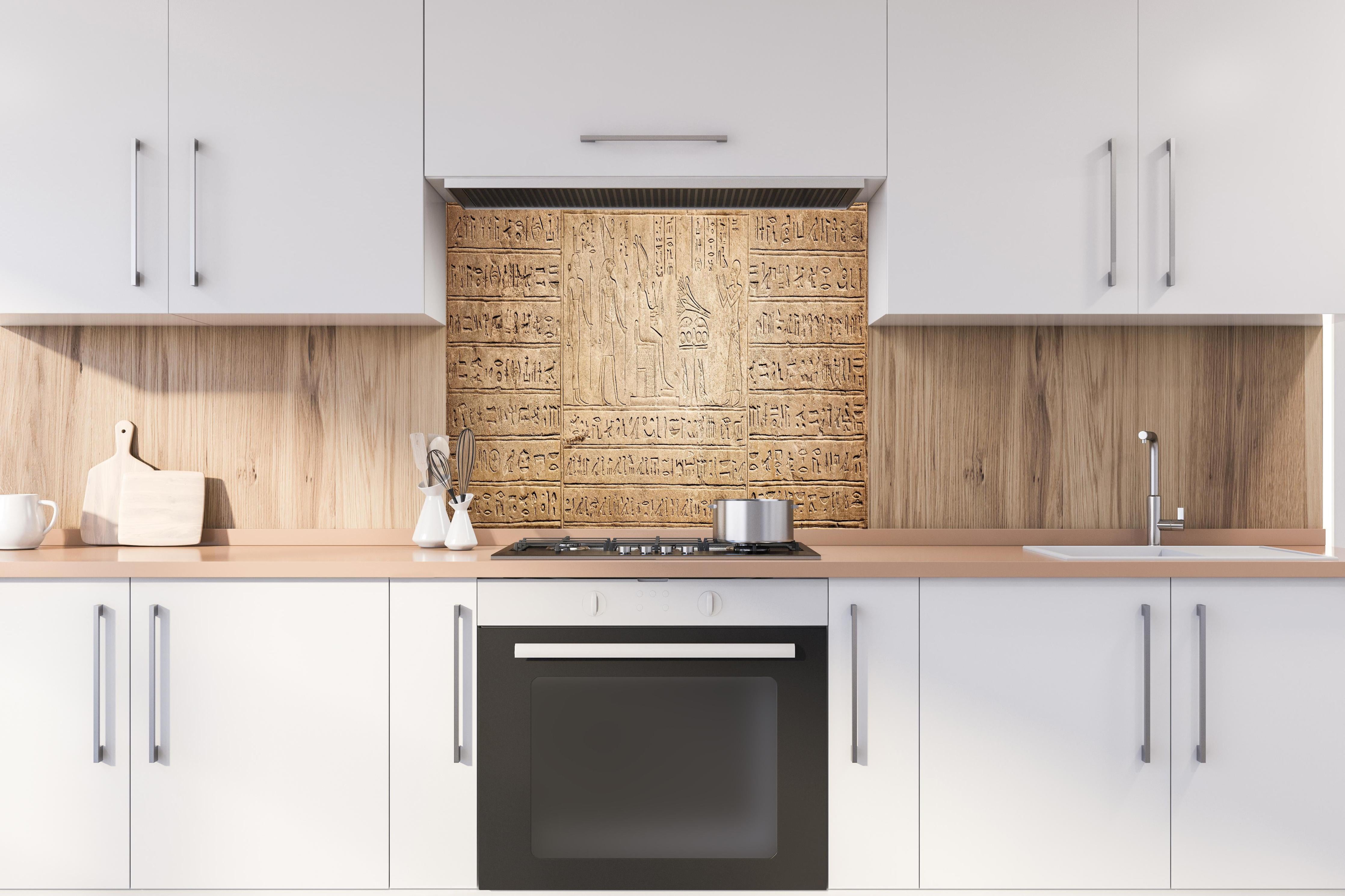 Spritzschutz - Ägyptische Hieroglyphen auf Sandstein hinter einem Cerankochfeld zwischen Holz-Kochutensilien
