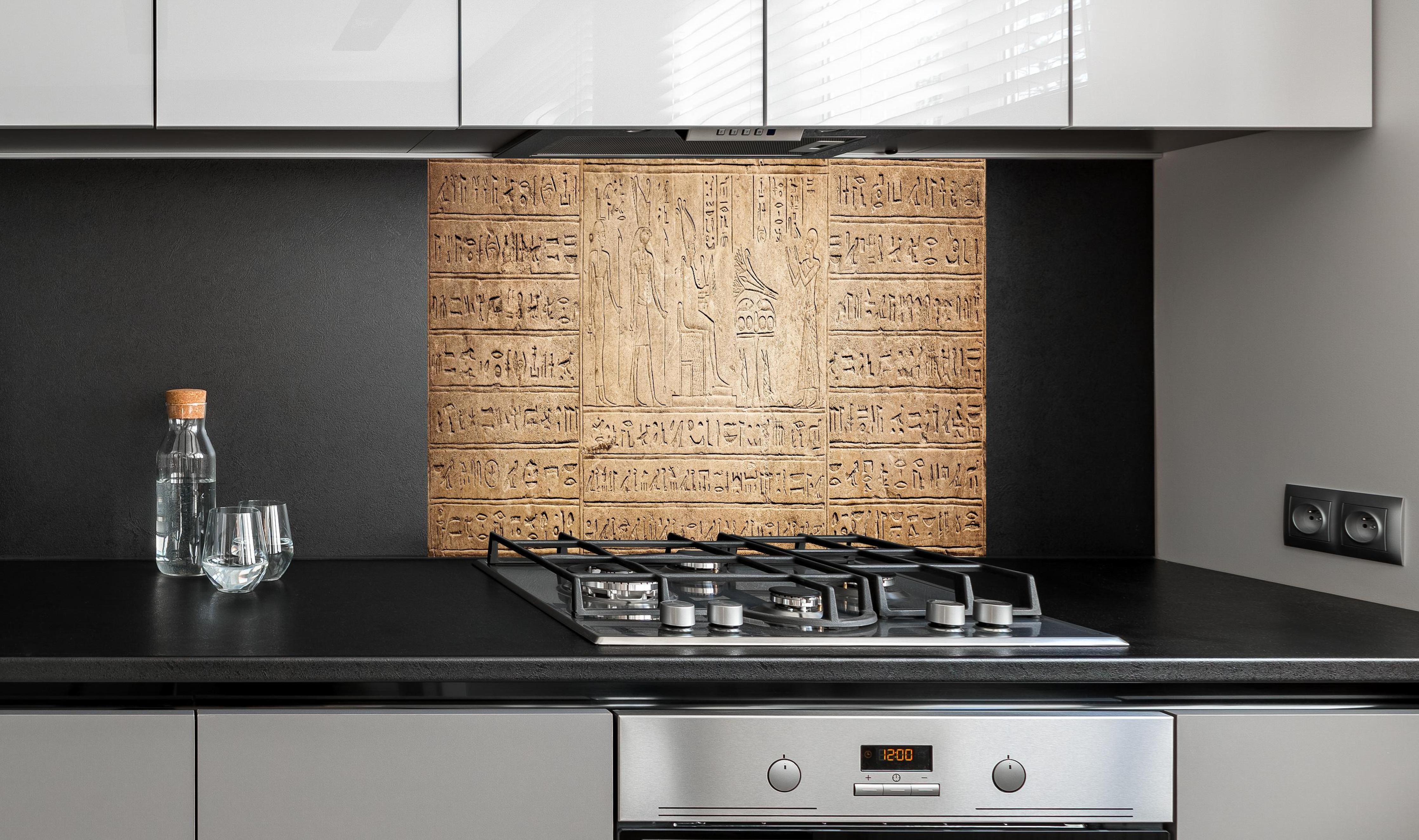 Spritzschutz - Ägyptische Hieroglyphen auf Sandstein hinter einem Cerankochfeld zwischen Holz-Kochutensilien
