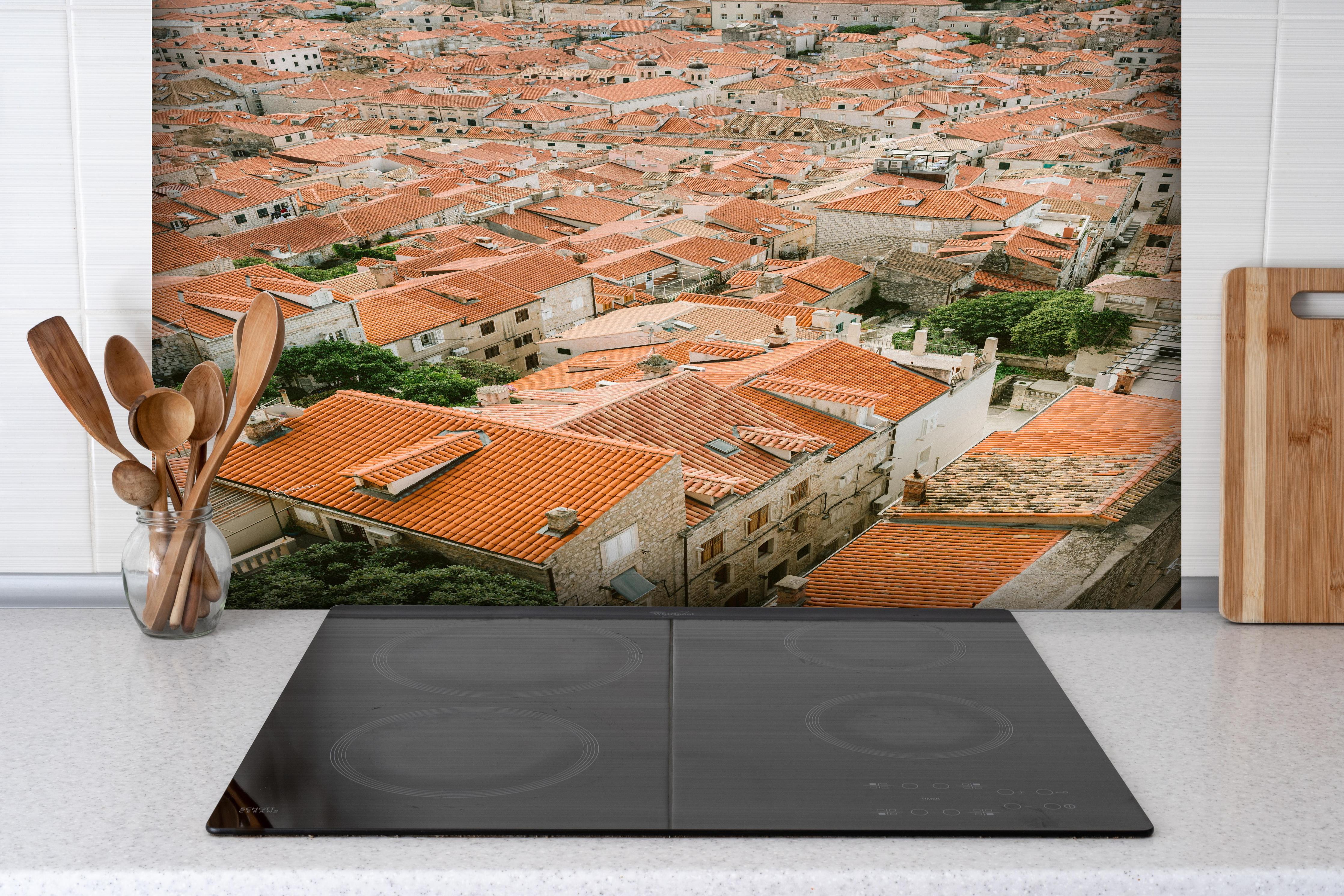 Spritzschutz - Alte Dachlandschaft Dubrovnik Kroatien hinter einem Cerankochfeld zwischen Holz-Kochutensilien
