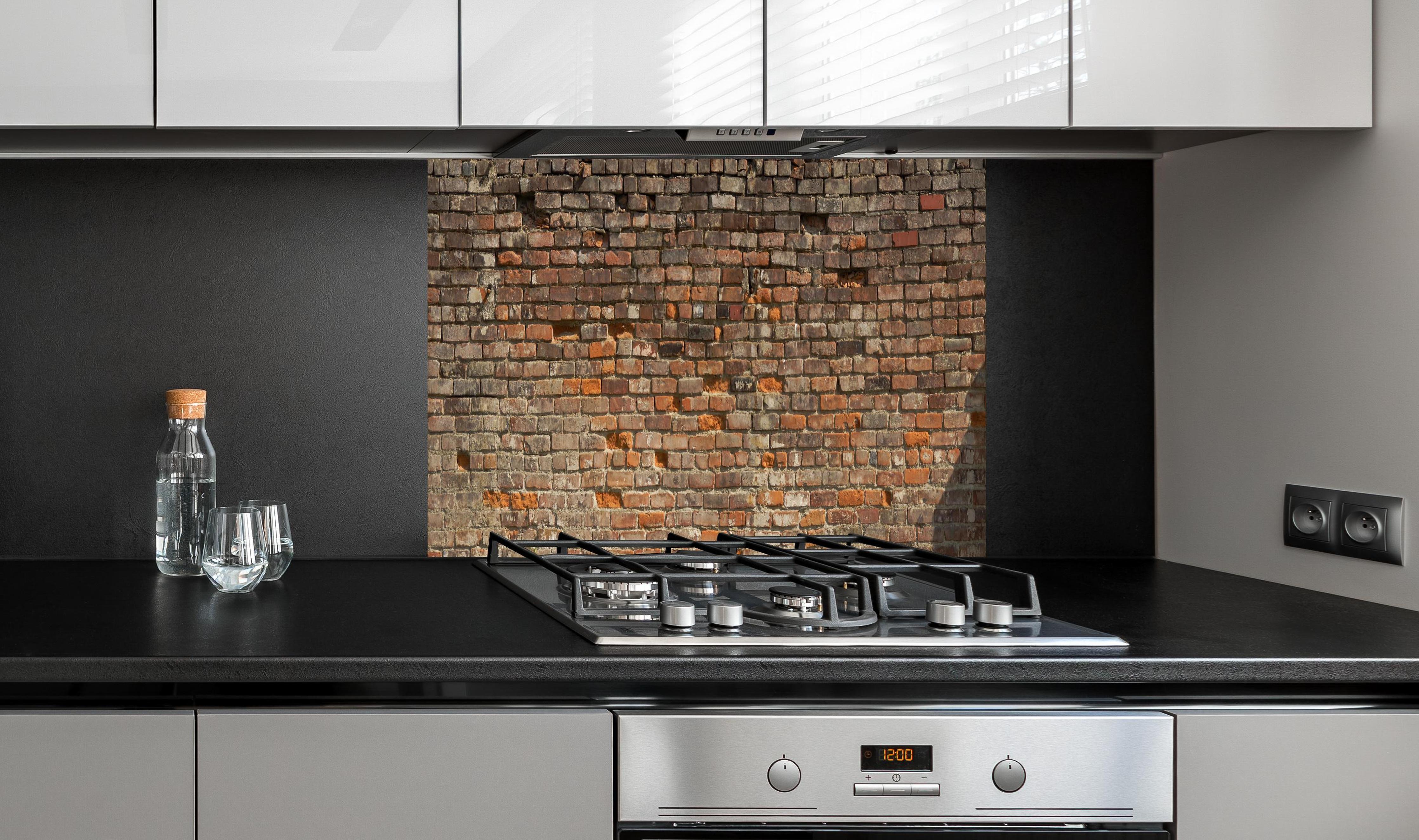 Spritzschutz - Alte kaputte Ziegelwand hinter einem Cerankochfeld zwischen Holz-Kochutensilien
