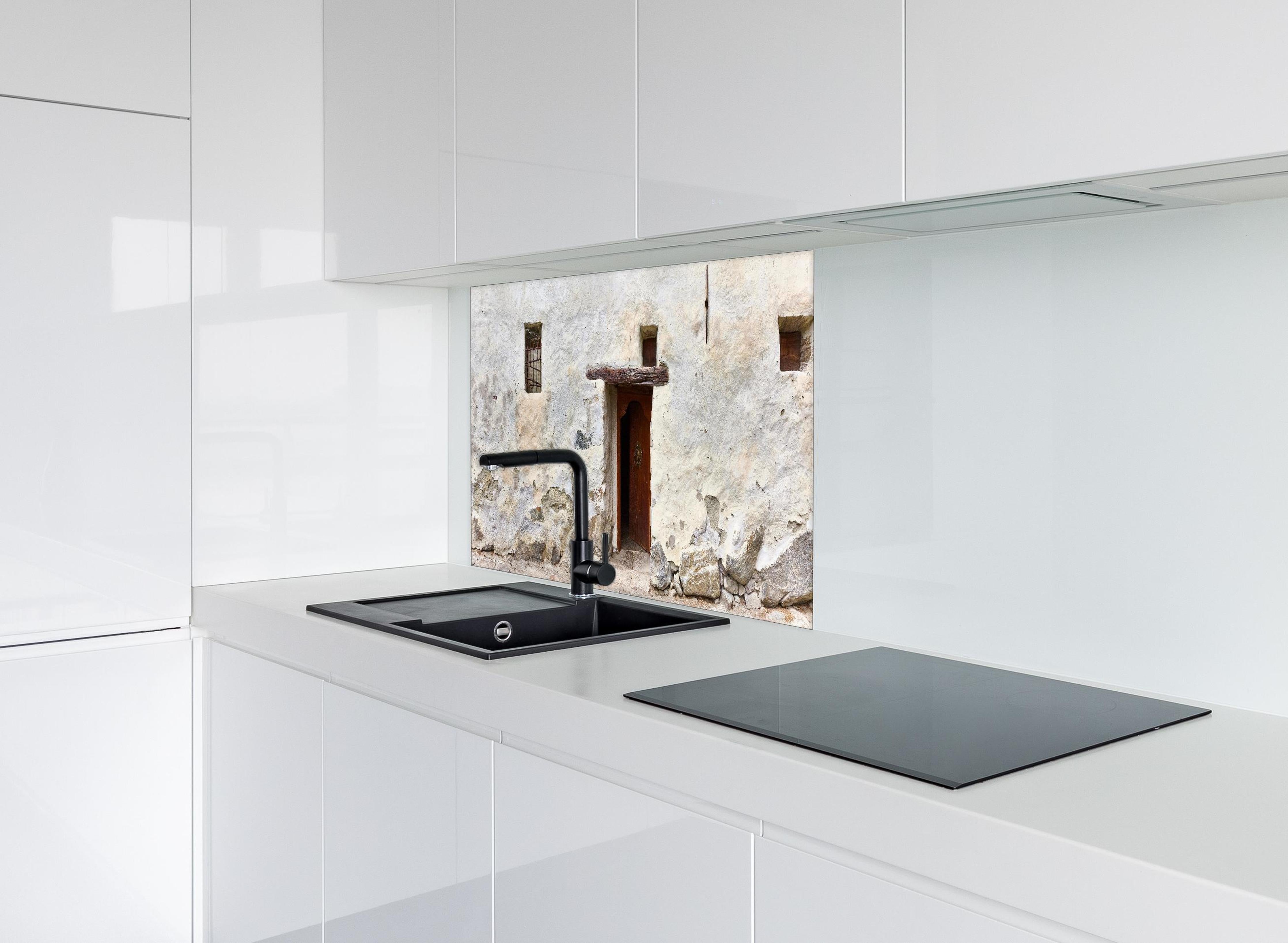 Spritzschutz - Alter Türeingang in Südtirol hinter einem Cerankochfeld zwischen Holz-Kochutensilien
