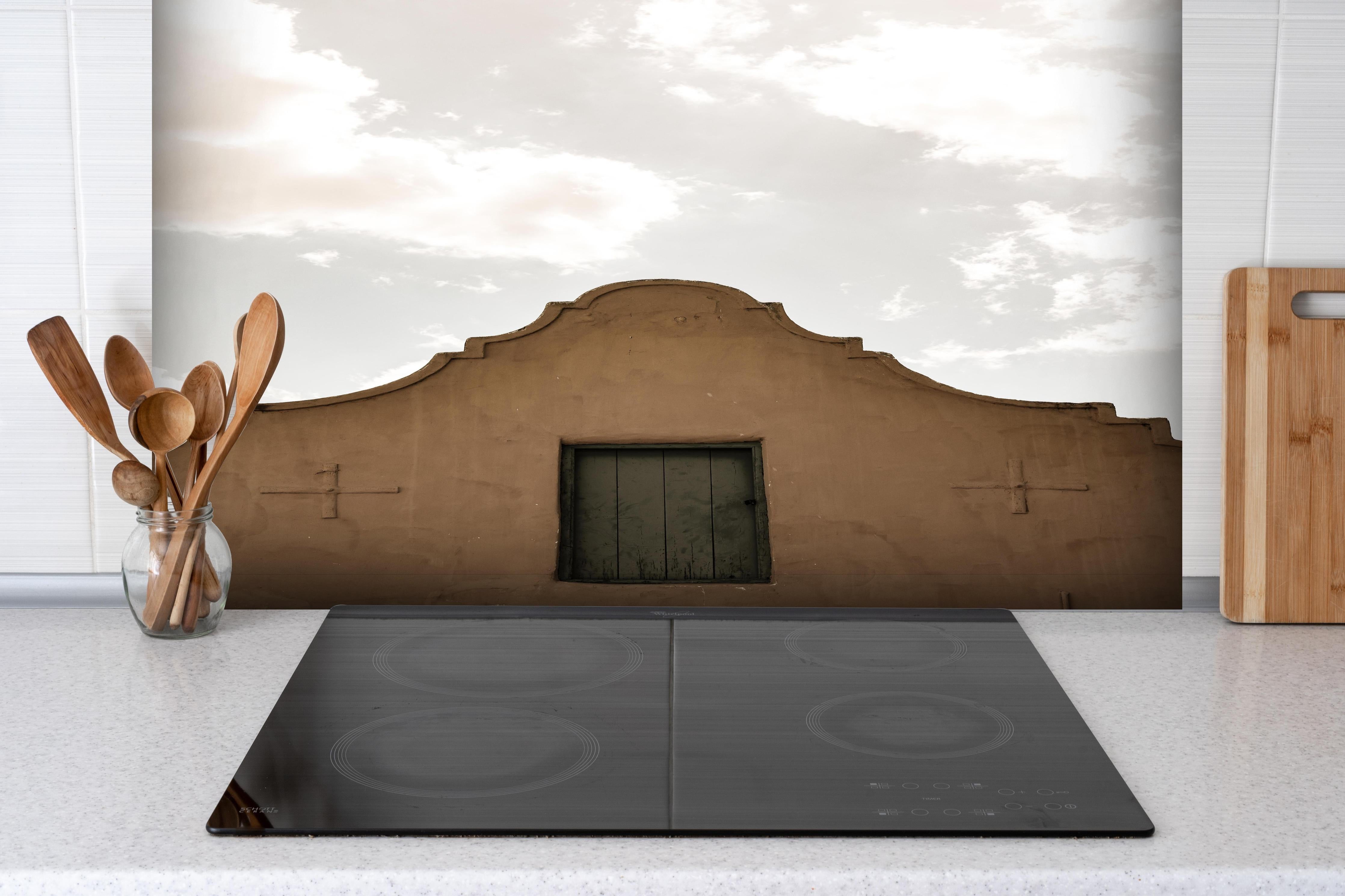 Spritzschutz - Altes Gebäude gegen bewölkten Himmel Kontrast hinter einem Cerankochfeld zwischen Holz-Kochutensilien
