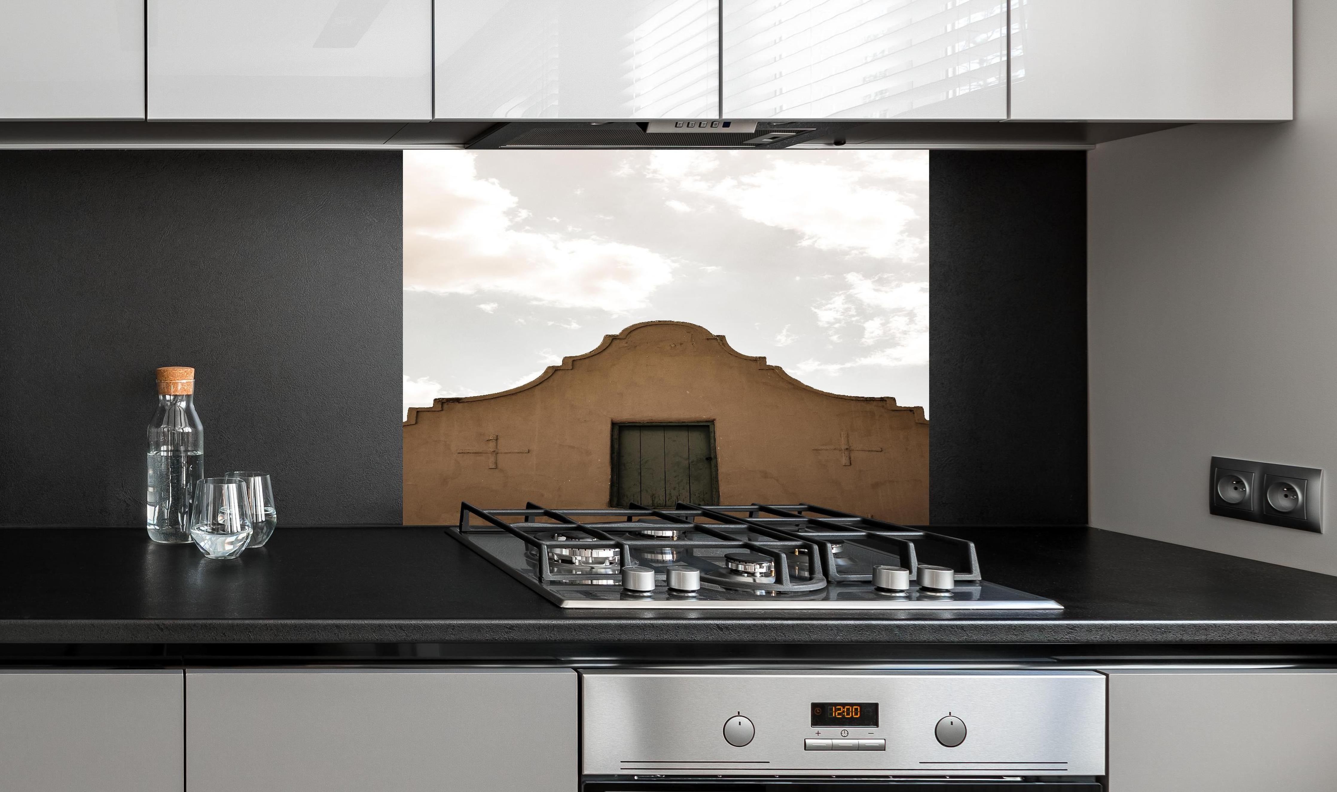 Spritzschutz - Altes Gebäude gegen bewölkten Himmel Kontrast hinter einem Cerankochfeld zwischen Holz-Kochutensilien
