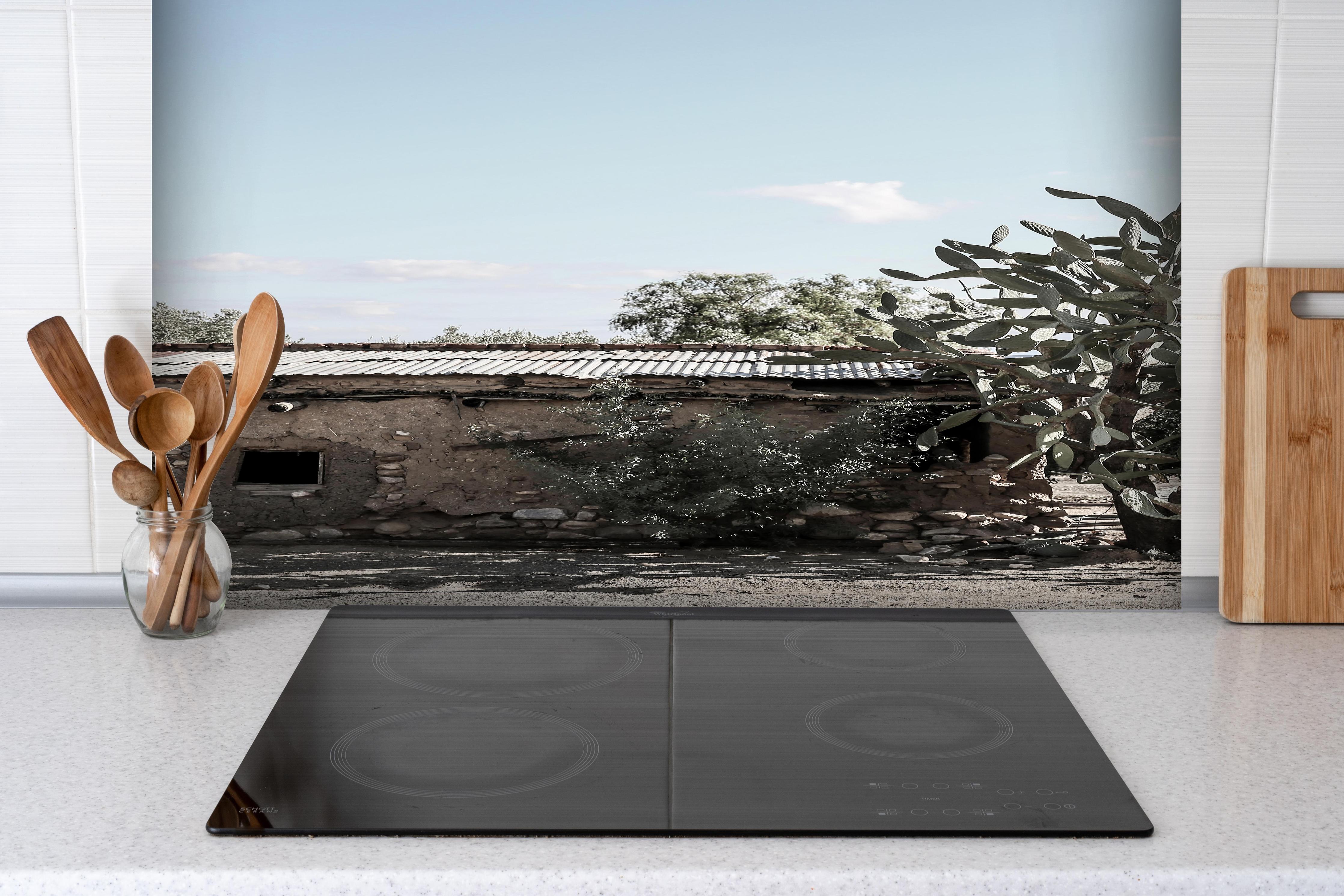 Spritzschutz - Altes Wüstenhaus mit Kakteenschatten hinter einem Cerankochfeld zwischen Holz-Kochutensilien
