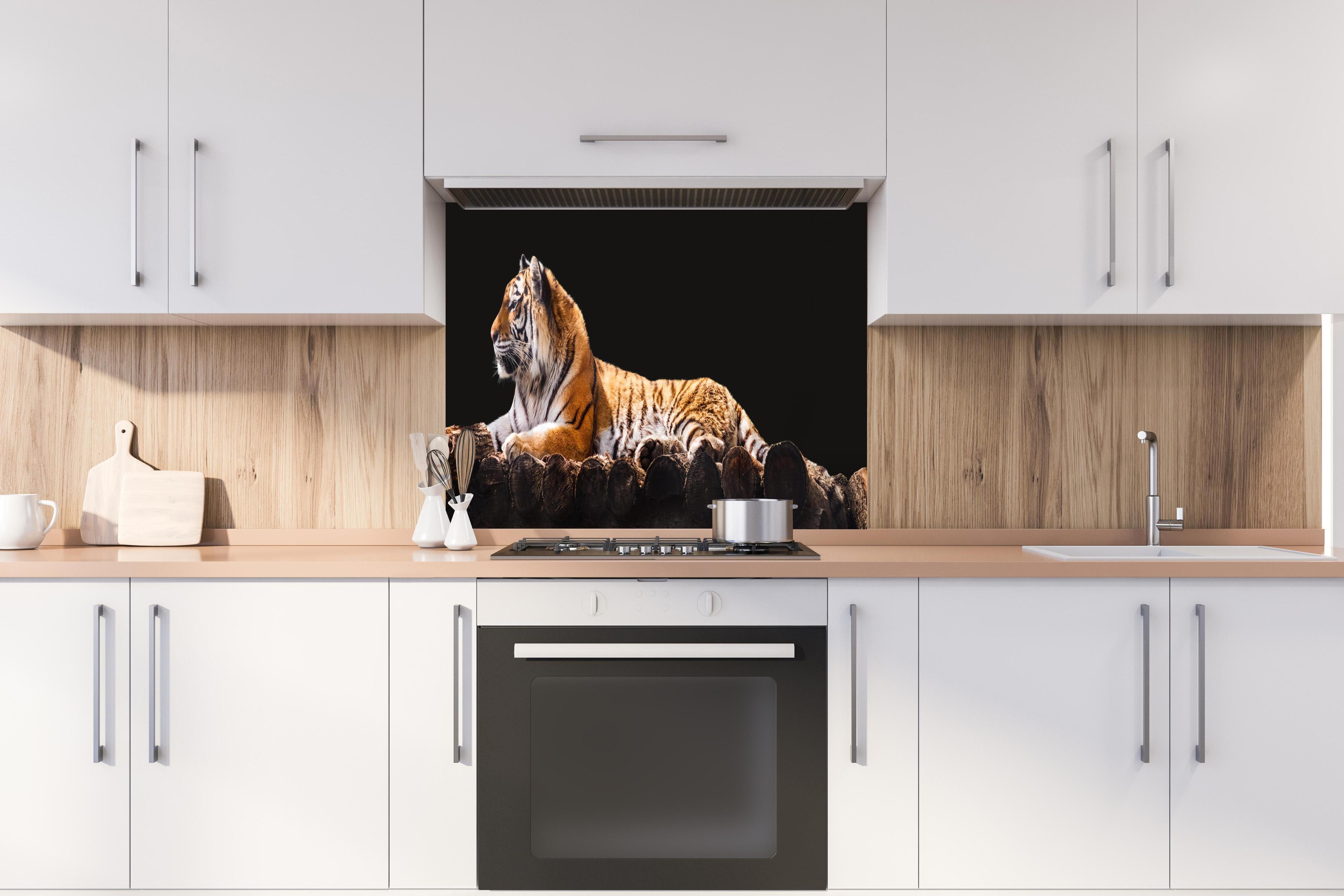 Spritzschutz - Amurtiger liegend auf Holzdeck mit Schwarzem Hintergrund hinter einem Cerankochfeld zwischen Holz-Kochutensilien
