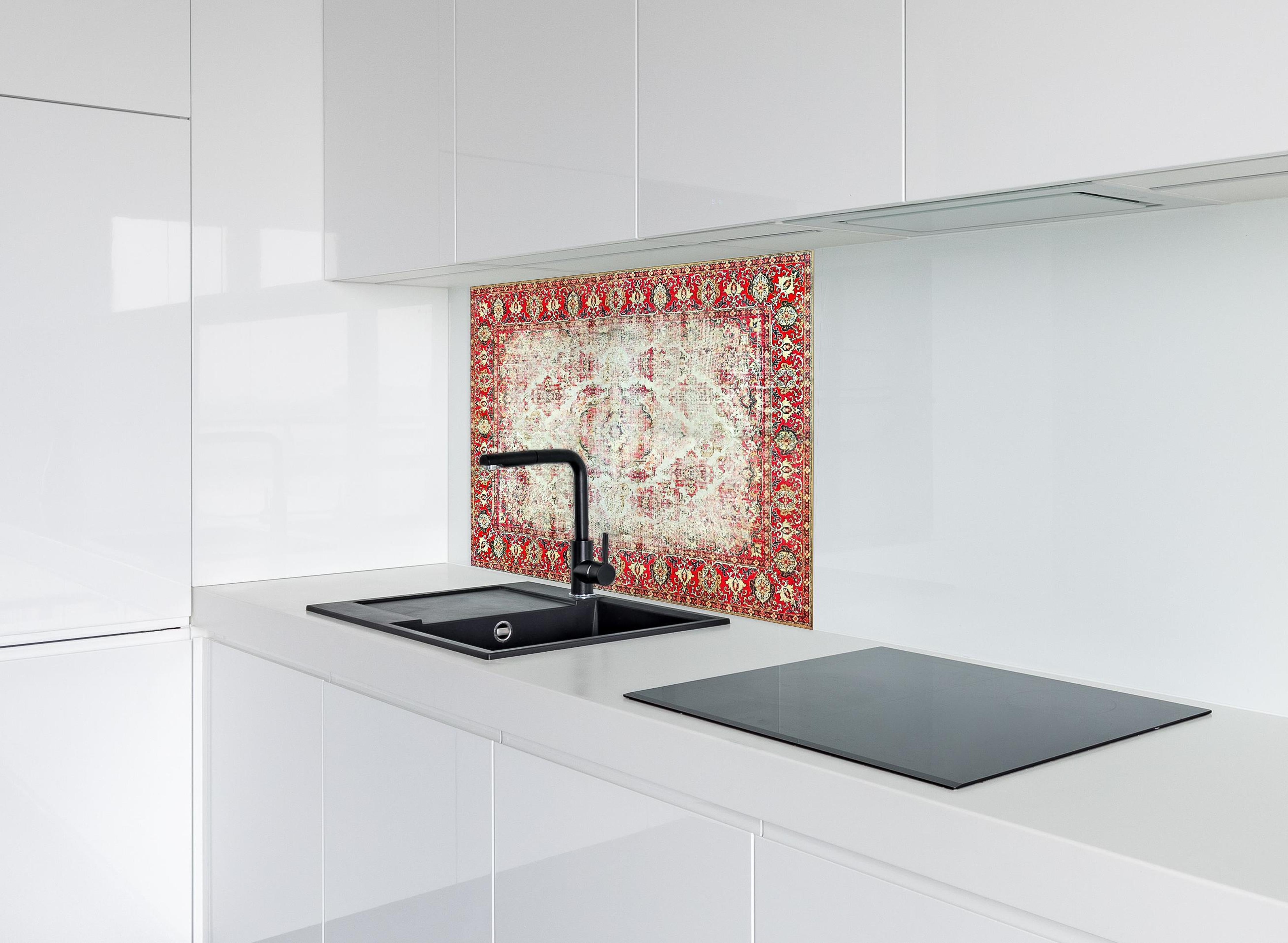 Spritzschutz - Antiker Rot-Beige-Wollteppich mit Muster hinter einem Cerankochfeld zwischen Holz-Kochutensilien
