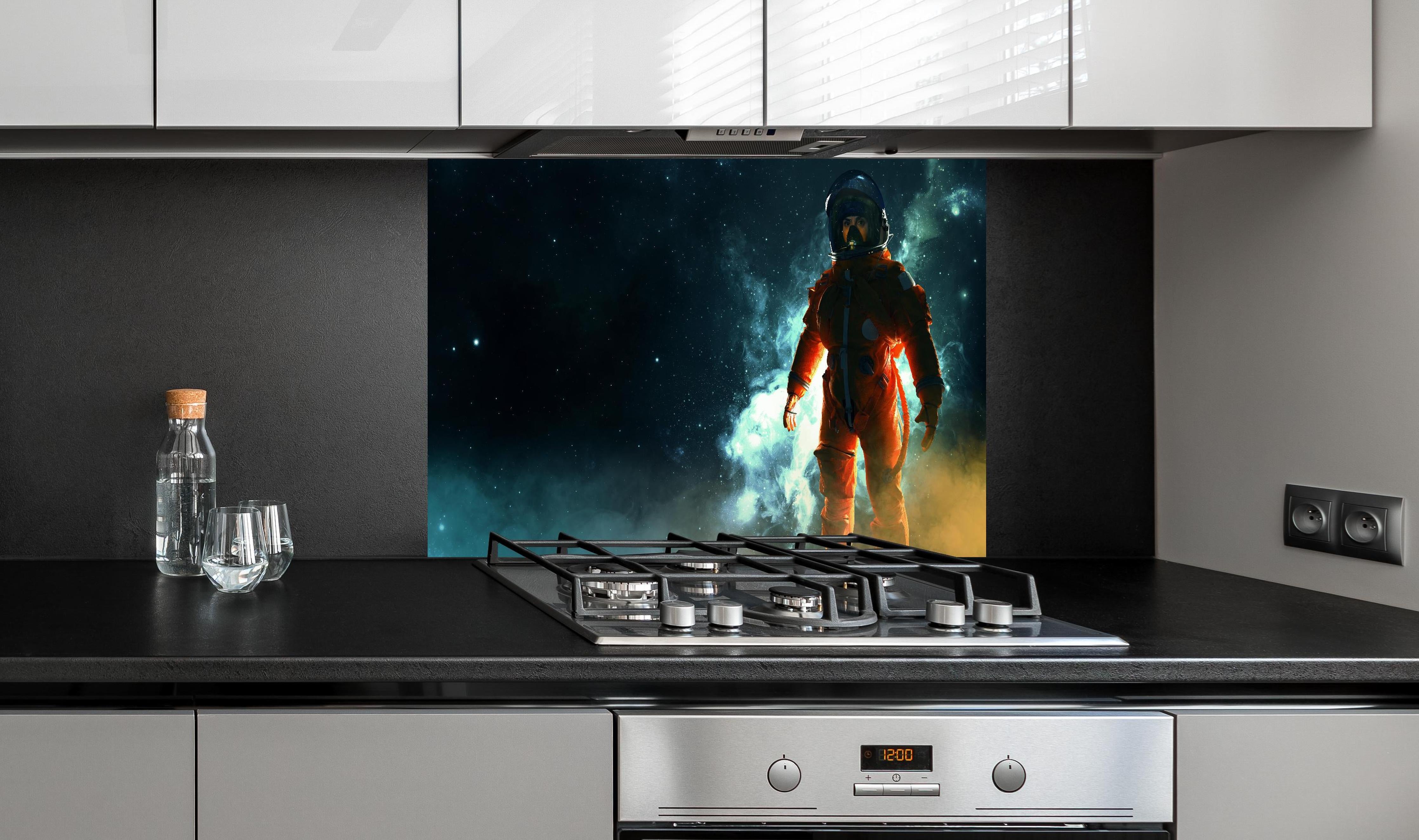 Spritzschutz - Astronaut im Weltraum hinter einem Cerankochfeld zwischen Holz-Kochutensilien
