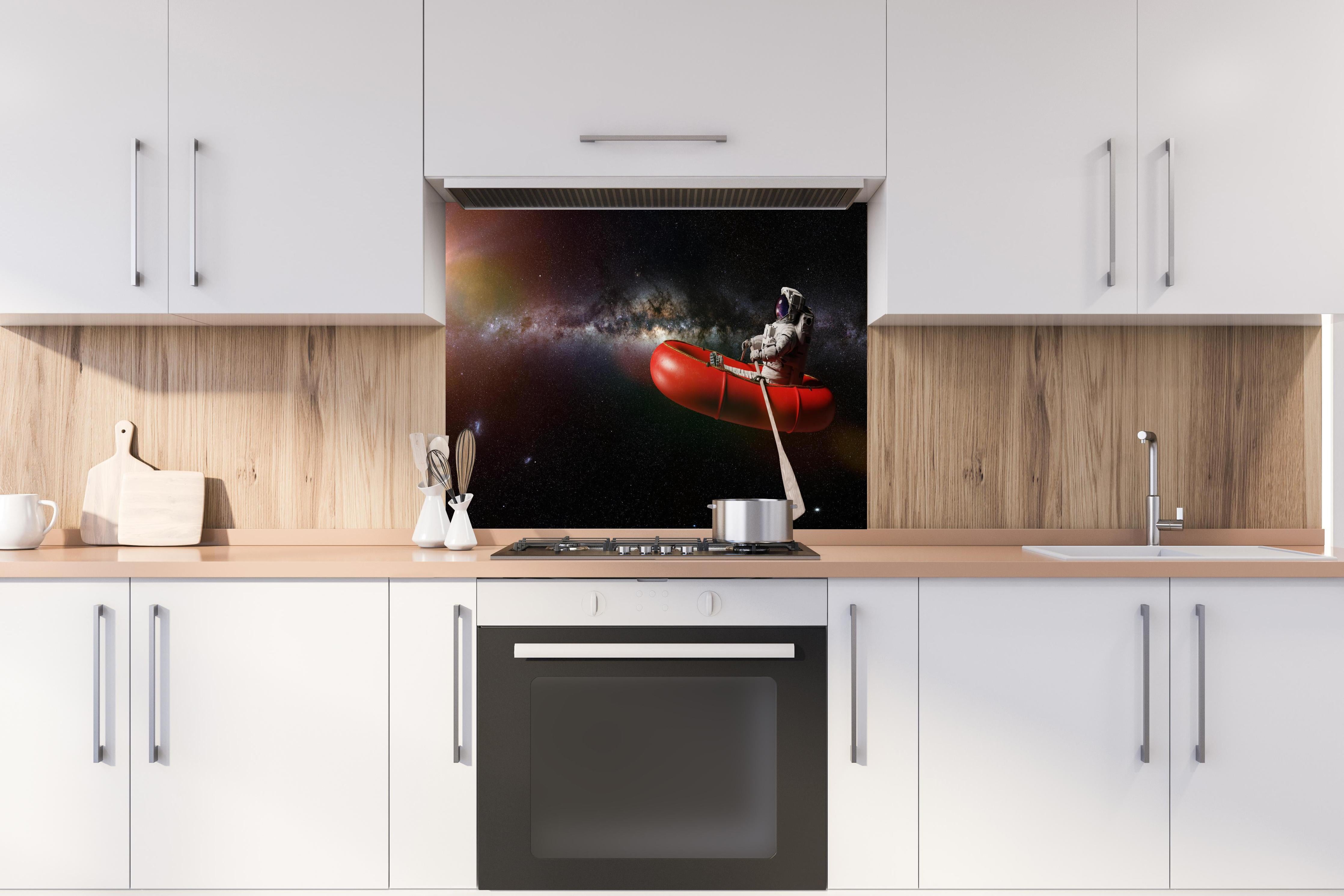 Spritzschutz - Astronaut treibt im Weltall auf Schlauchboot hinter einem Cerankochfeld zwischen Holz-Kochutensilien
