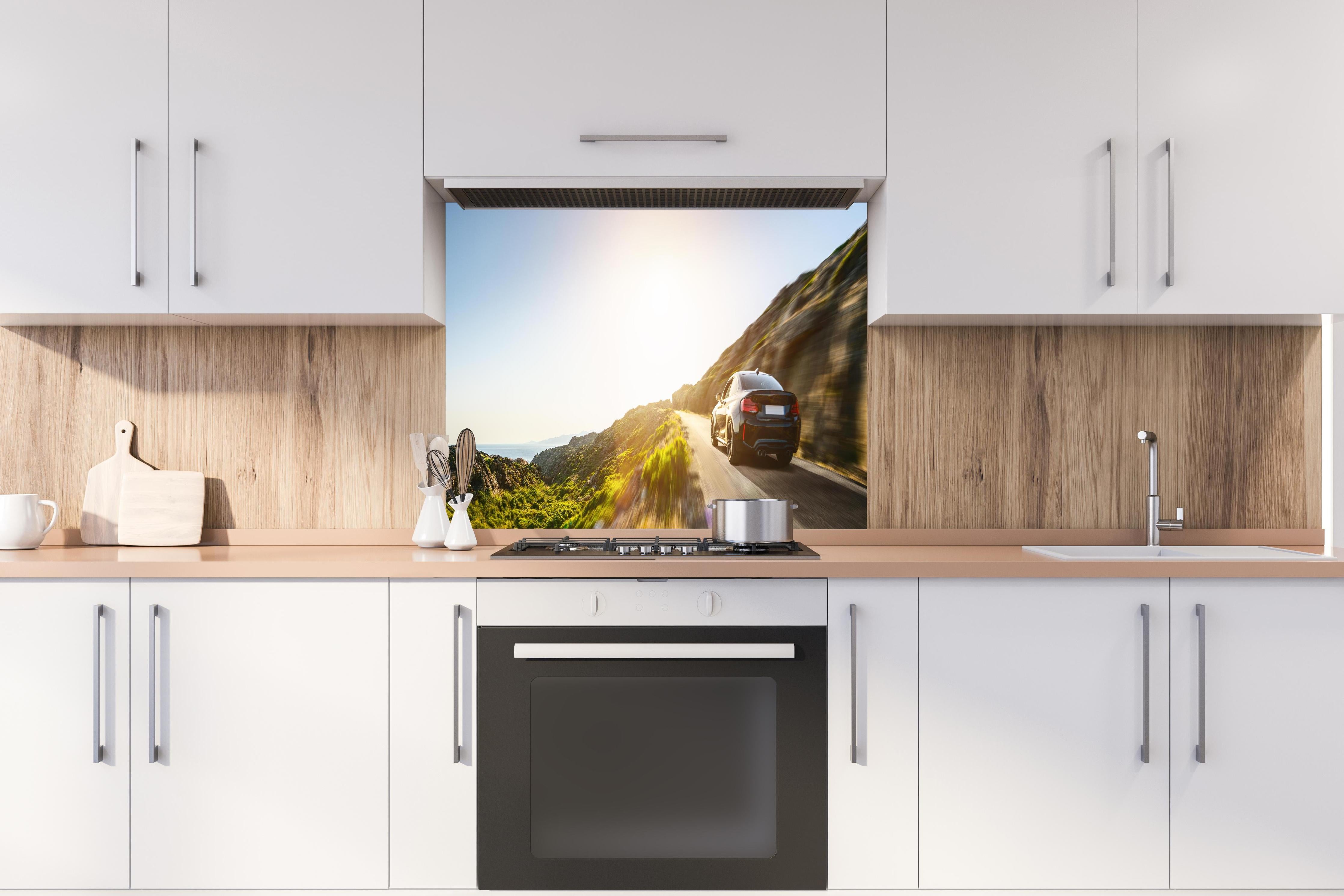 Spritzschutz - Auto fährt über eine Straße auf Bergen hinter einem Cerankochfeld zwischen Holz-Kochutensilien
