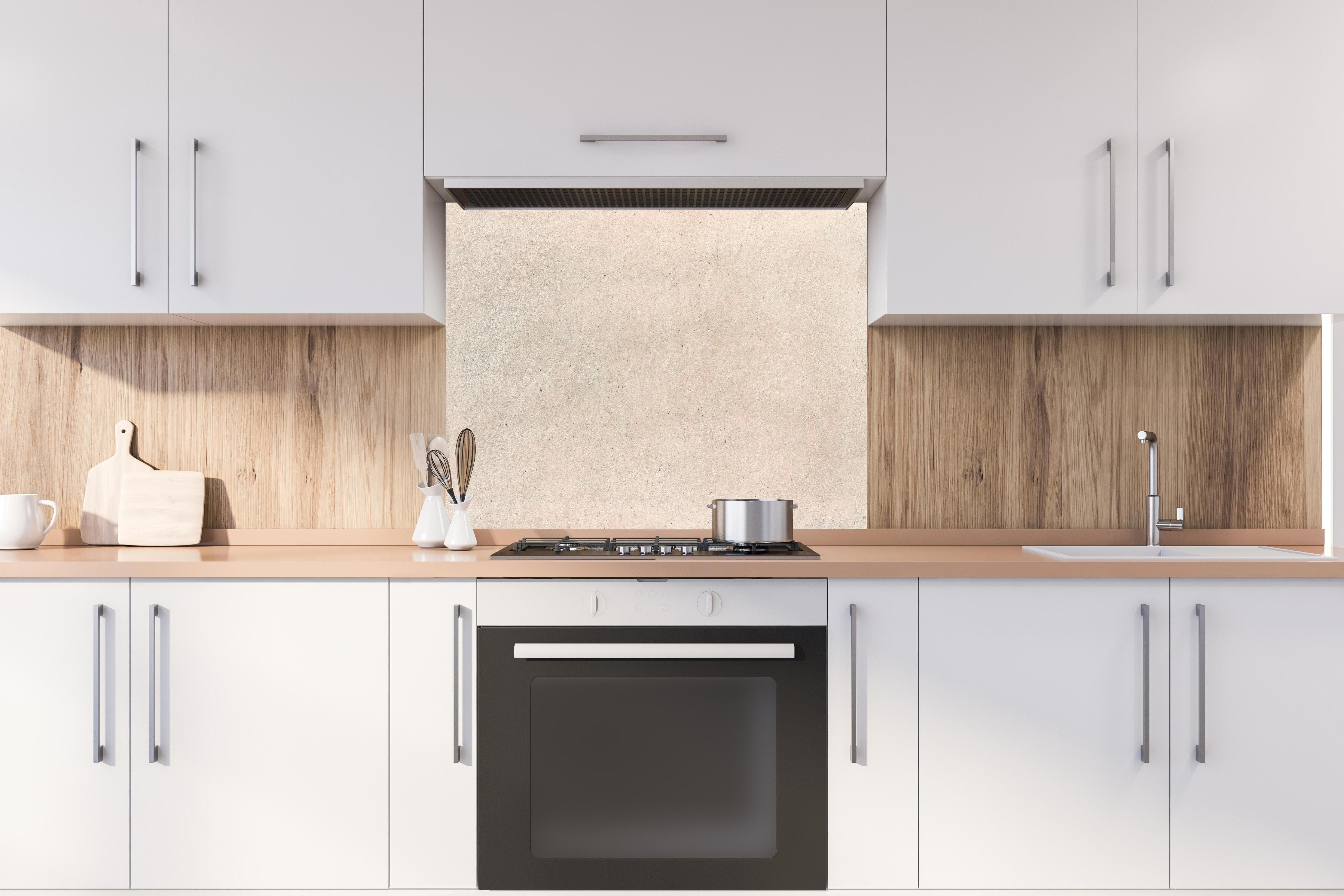 Spritzschutz - Beige Betonhintergrund hinter einem Cerankochfeld zwischen Holz-Kochutensilien
