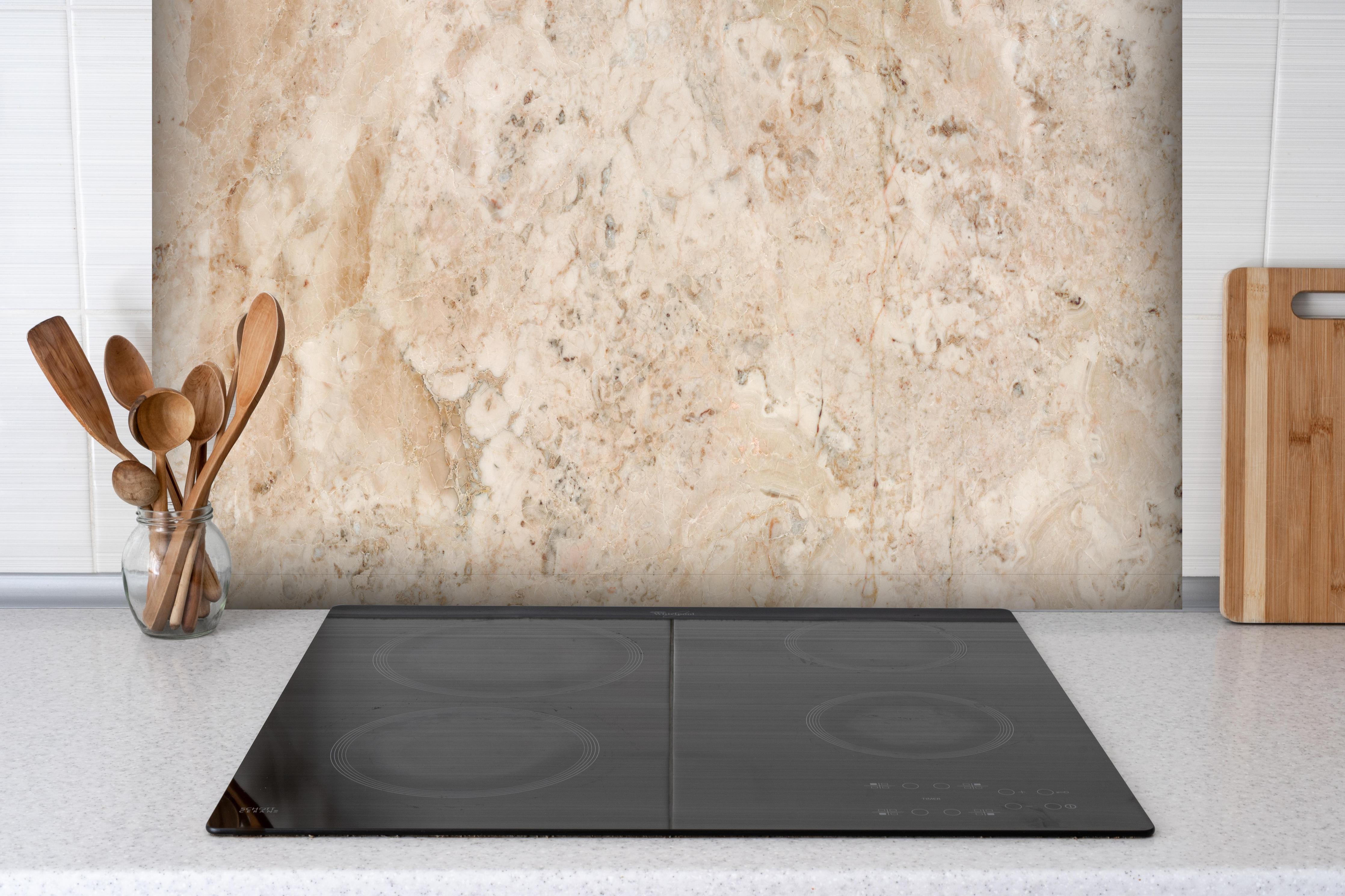 Spritzschutz - Beige Naturmarmor Stein Textur hinter einem Cerankochfeld zwischen Holz-Kochutensilien
