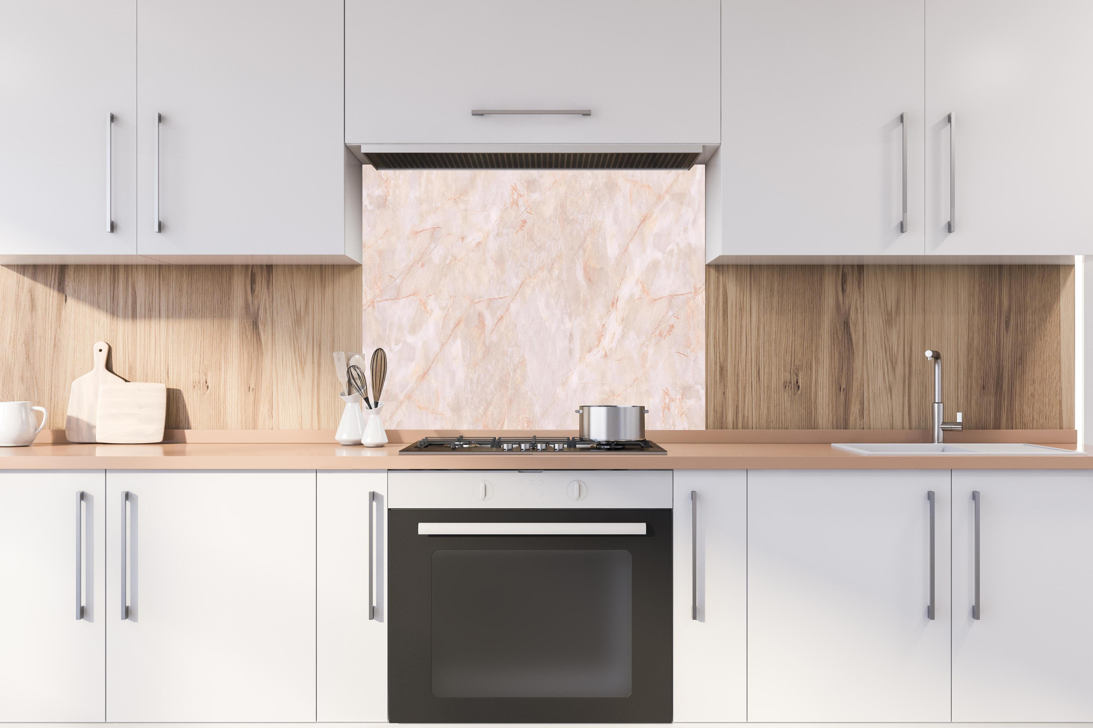 Spritzschutz - Beige-Rosa Marmorstein hinter einem Cerankochfeld zwischen Holz-Kochutensilien
