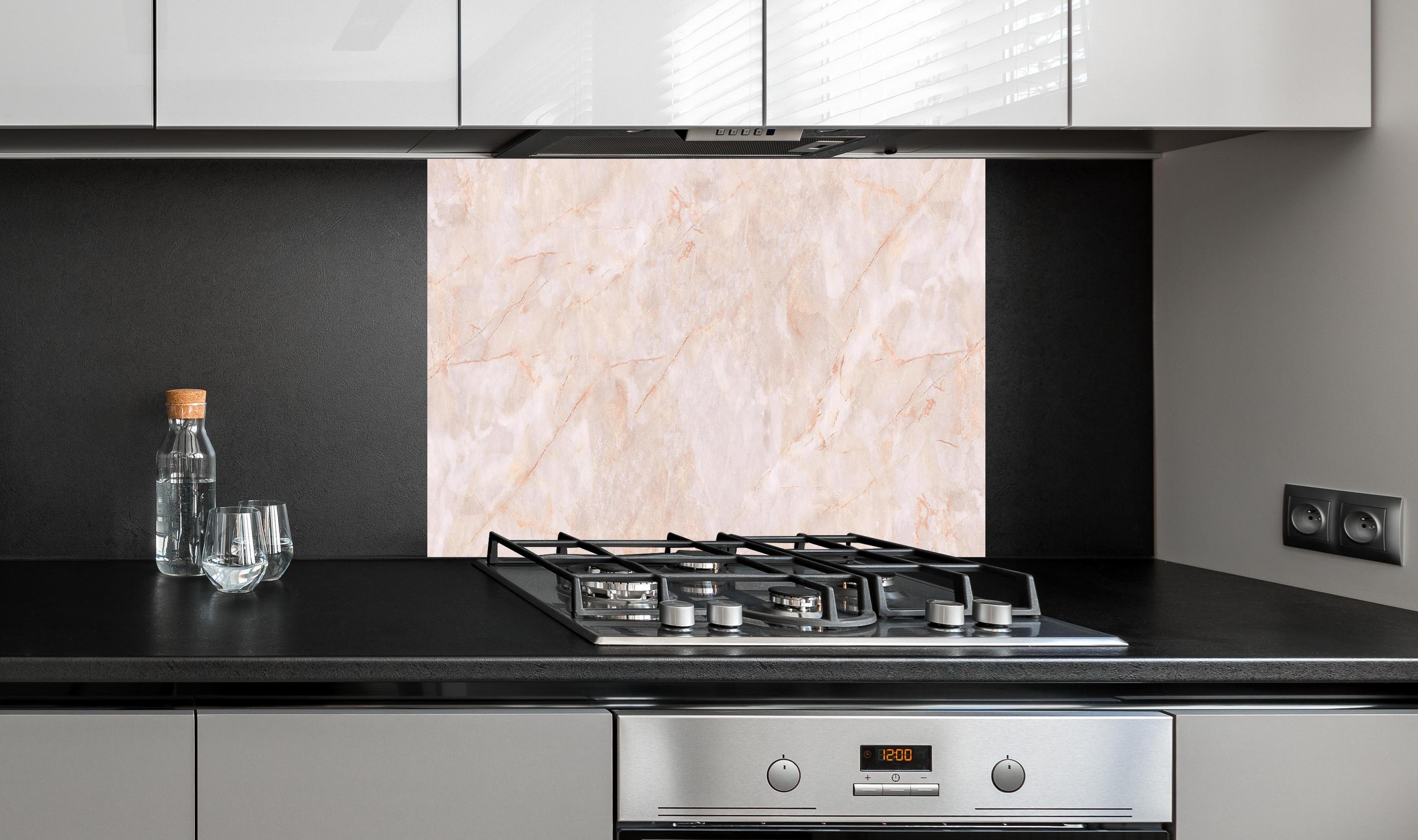 Spritzschutz - Beige-Rosa Marmorstein hinter einem Cerankochfeld zwischen Holz-Kochutensilien

