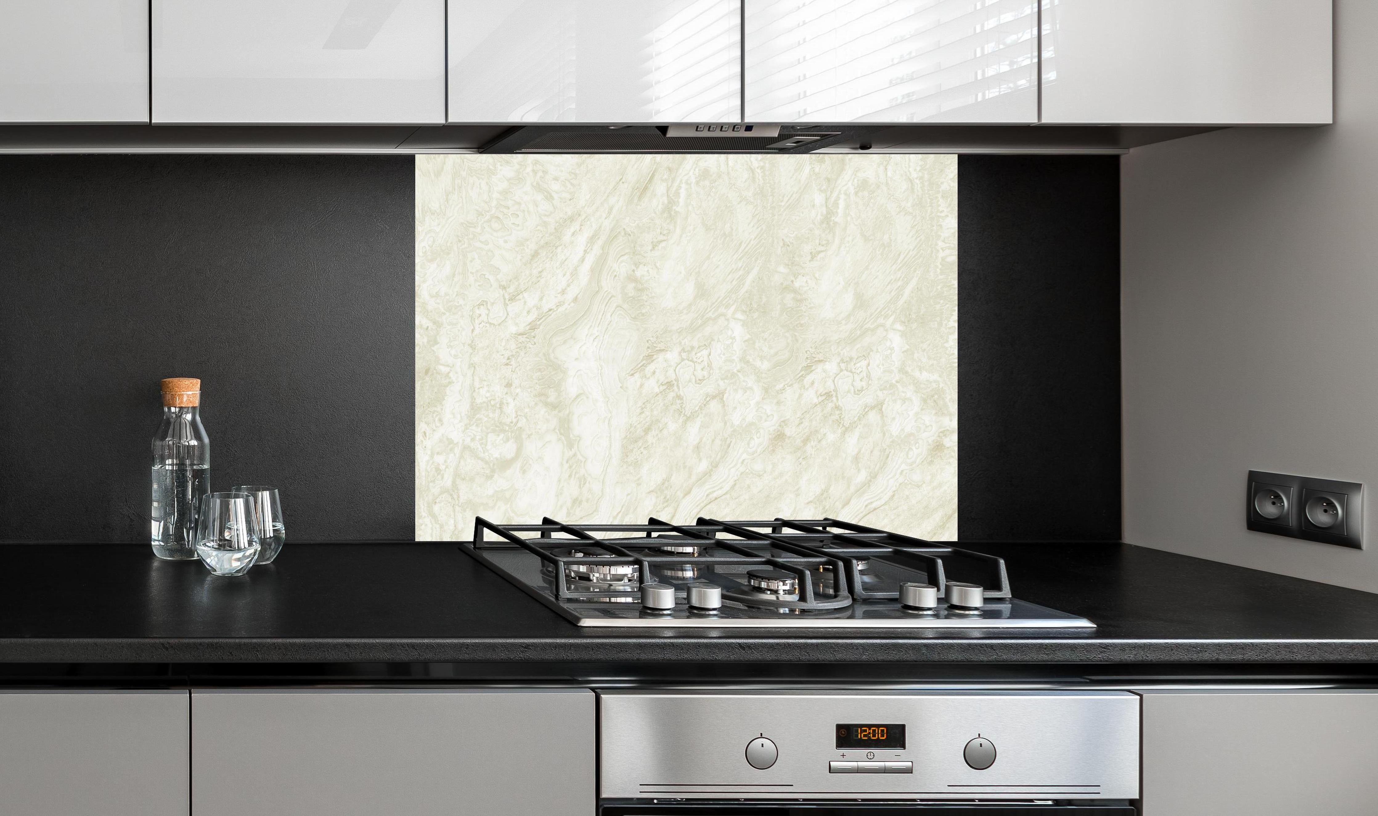 Spritzschutz - Beige-Weißer Marmor hinter einem Cerankochfeld zwischen Holz-Kochutensilien
