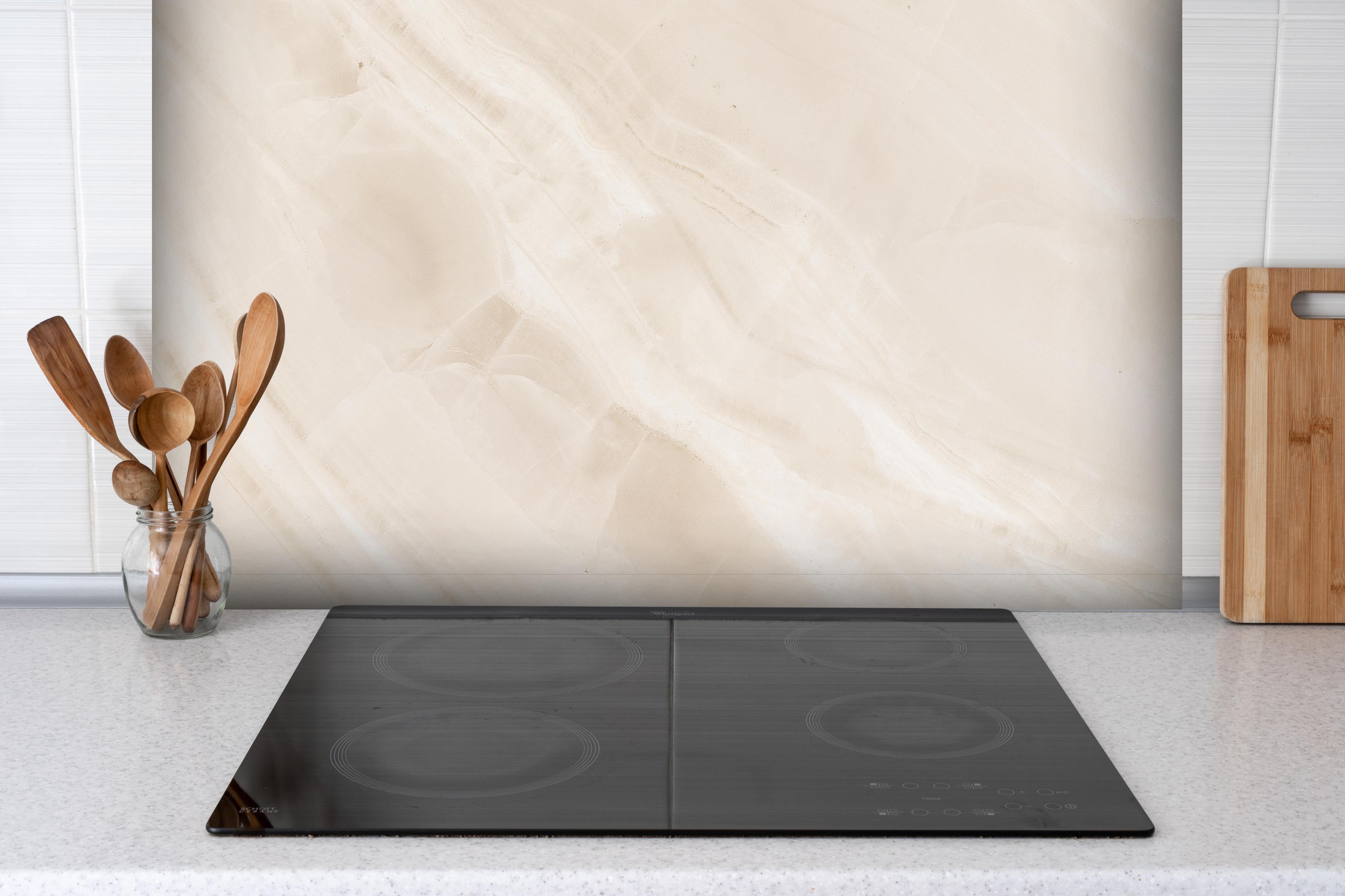 Spritzschutz - Beige natürliche Marmortextur hinter einem Cerankochfeld zwischen Holz-Kochutensilien
