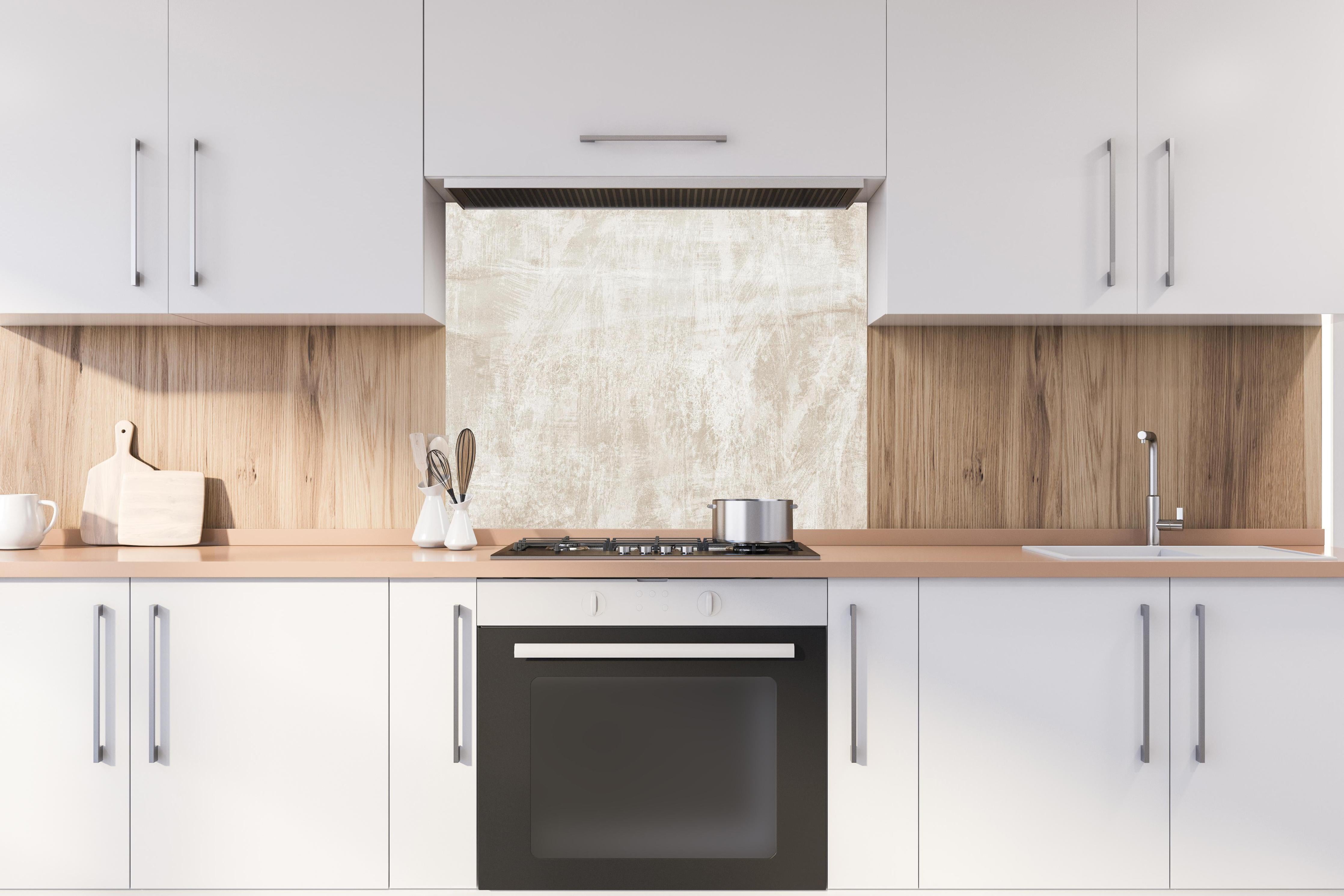 Spritzschutz - Beigefarbener Hintergrund hinter einem Cerankochfeld zwischen Holz-Kochutensilien
