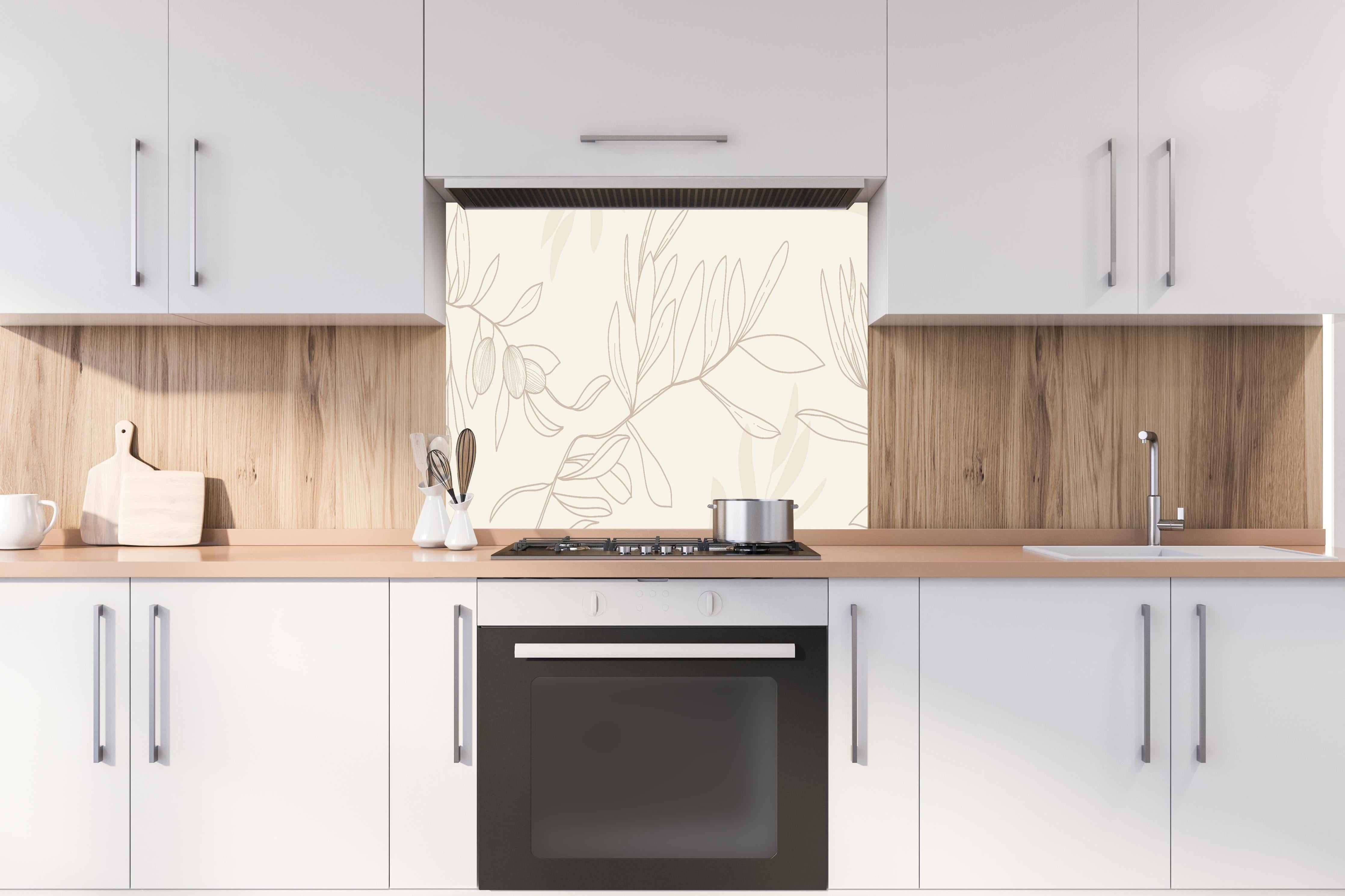 Spritzschutz - Beiger Olivenzweig hinter einem Cerankochfeld zwischen Holz-Kochutensilien
