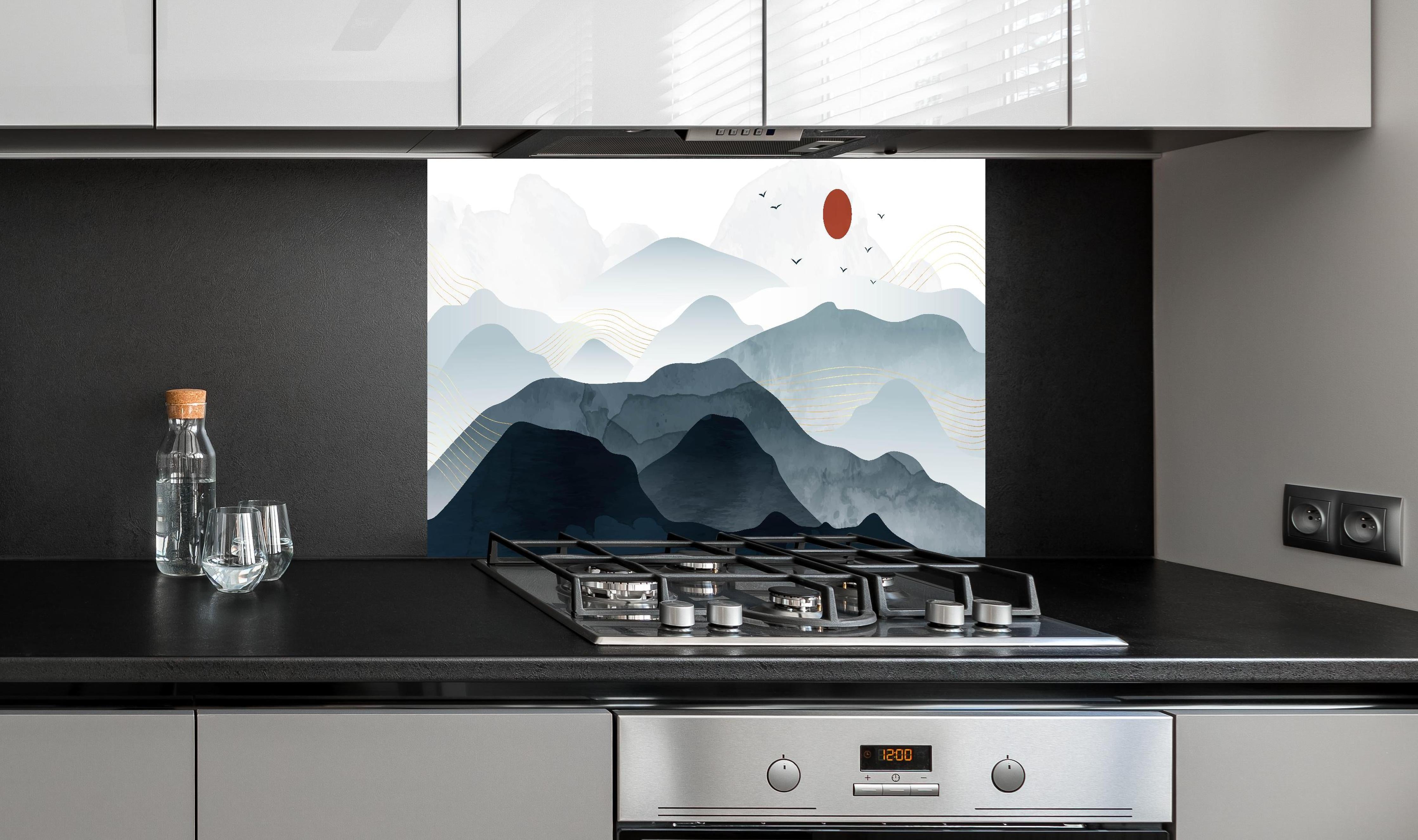 Spritzschutz - Bergpanorama mit rotem Sonnenkreis Kunst hinter einem Cerankochfeld zwischen Holz-Kochutensilien
