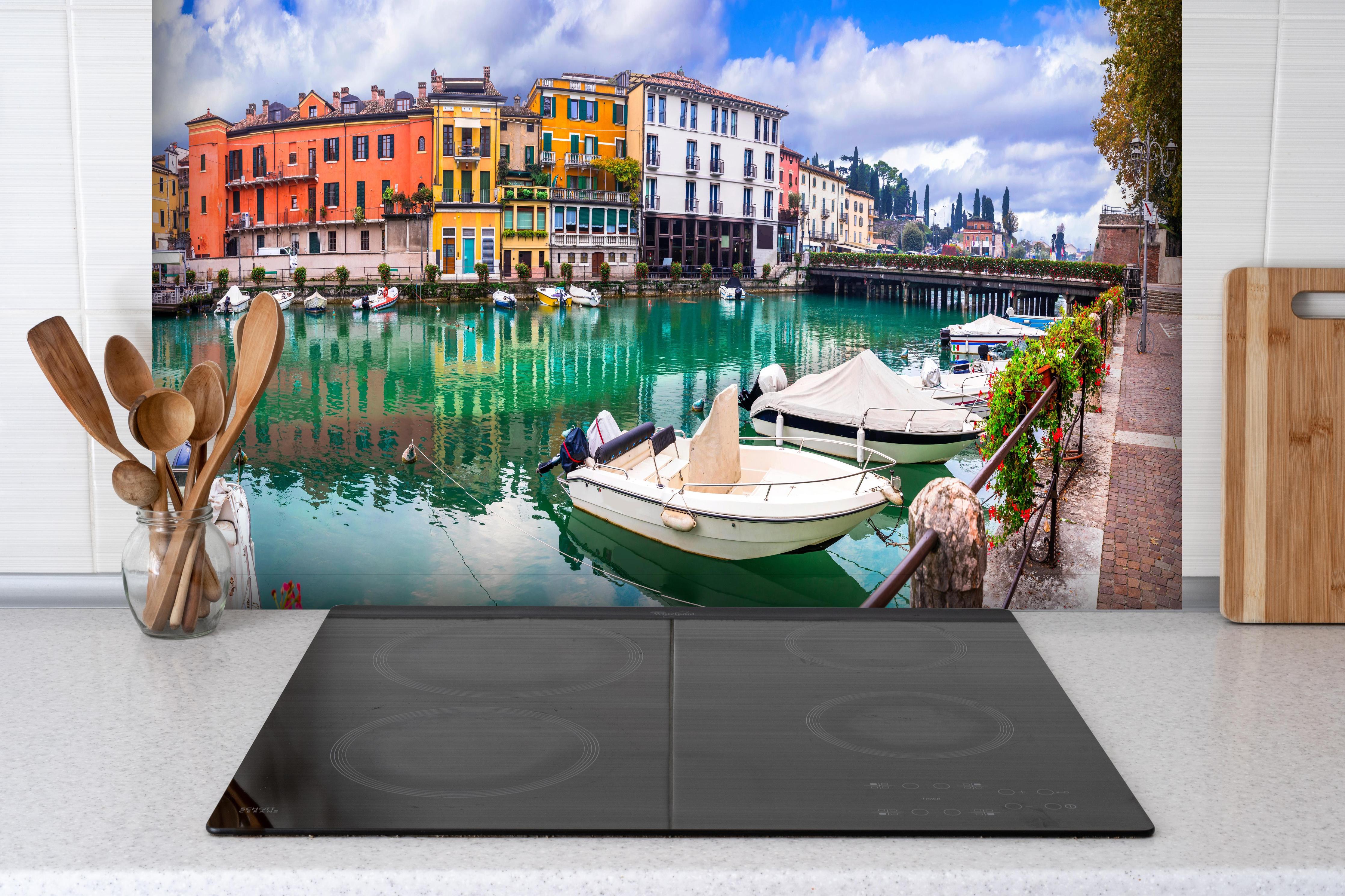 Spritzschutz - Beschauliches schönes Dorf in Peschie hinter einem Cerankochfeld zwischen Holz-Kochutensilien
