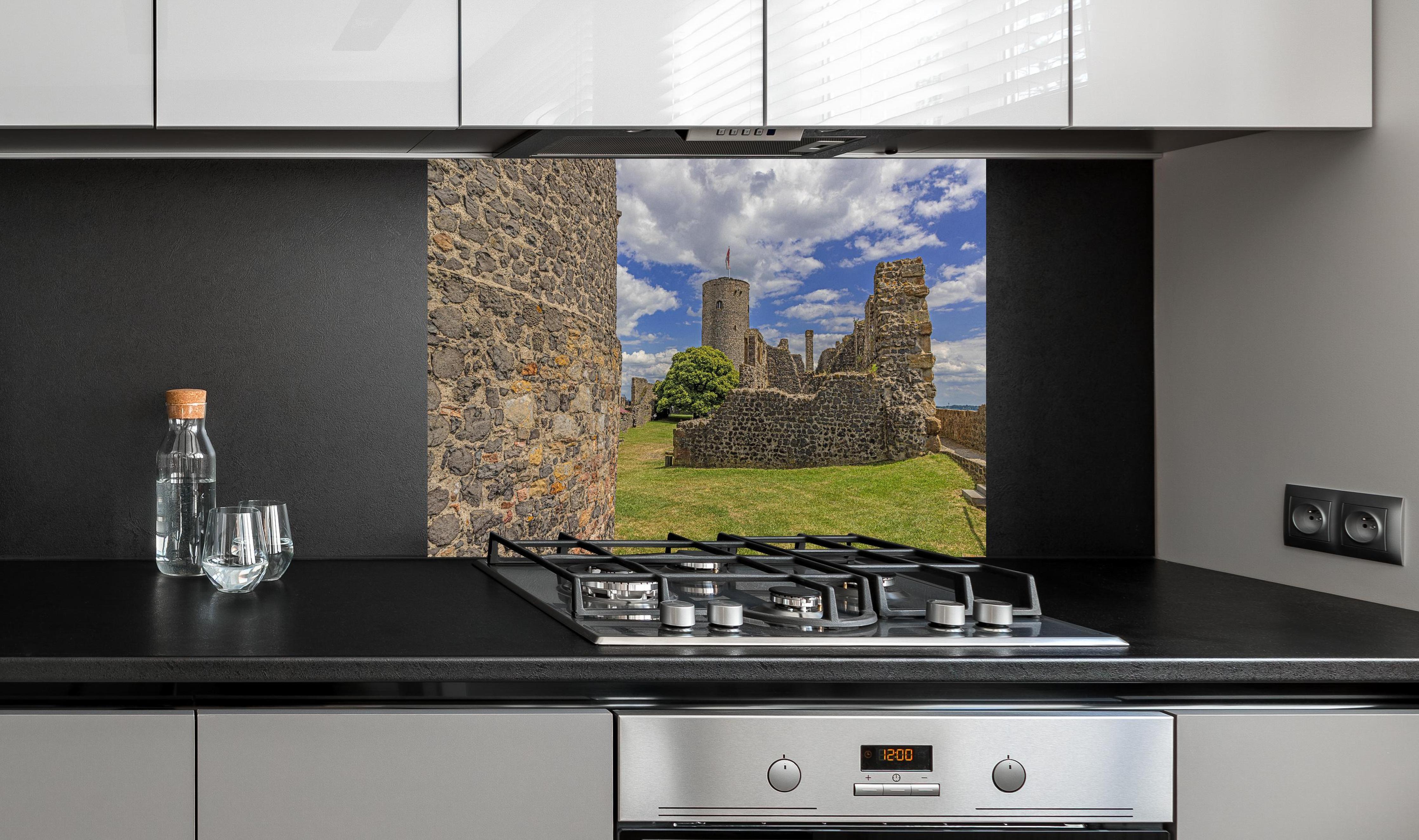 Spritzschutz - Bild von der Burgruine Münzenberg in Hessen hinter einem Cerankochfeld zwischen Holz-Kochutensilien
