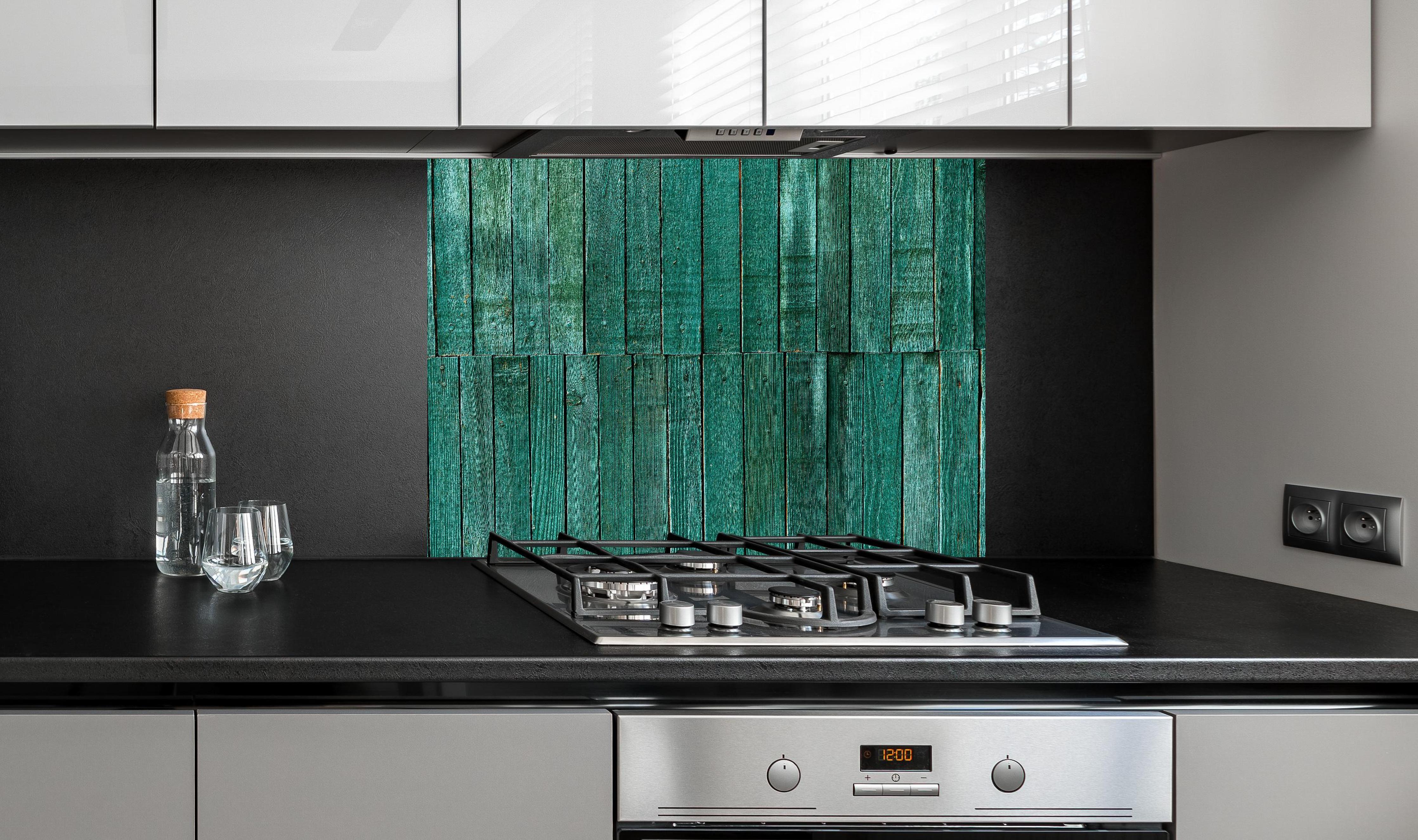 Spritzschutz - Bläuliche Holzbretter hinter einem Cerankochfeld zwischen Holz-Kochutensilien
