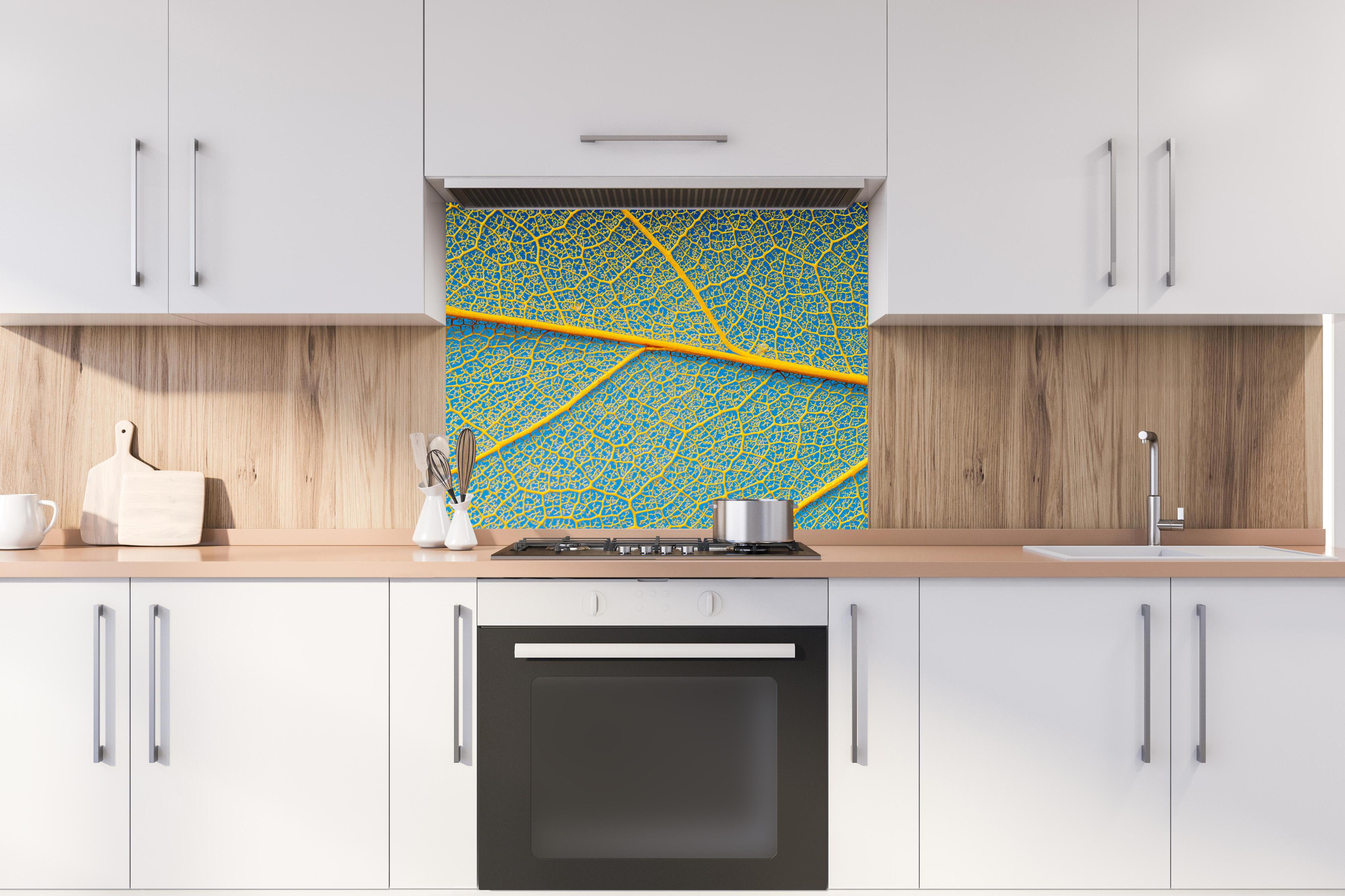 Spritzschutz - Blattstruktur in Makroaufnahme Gelb-Blau hinter einem Cerankochfeld zwischen Holz-Kochutensilien
