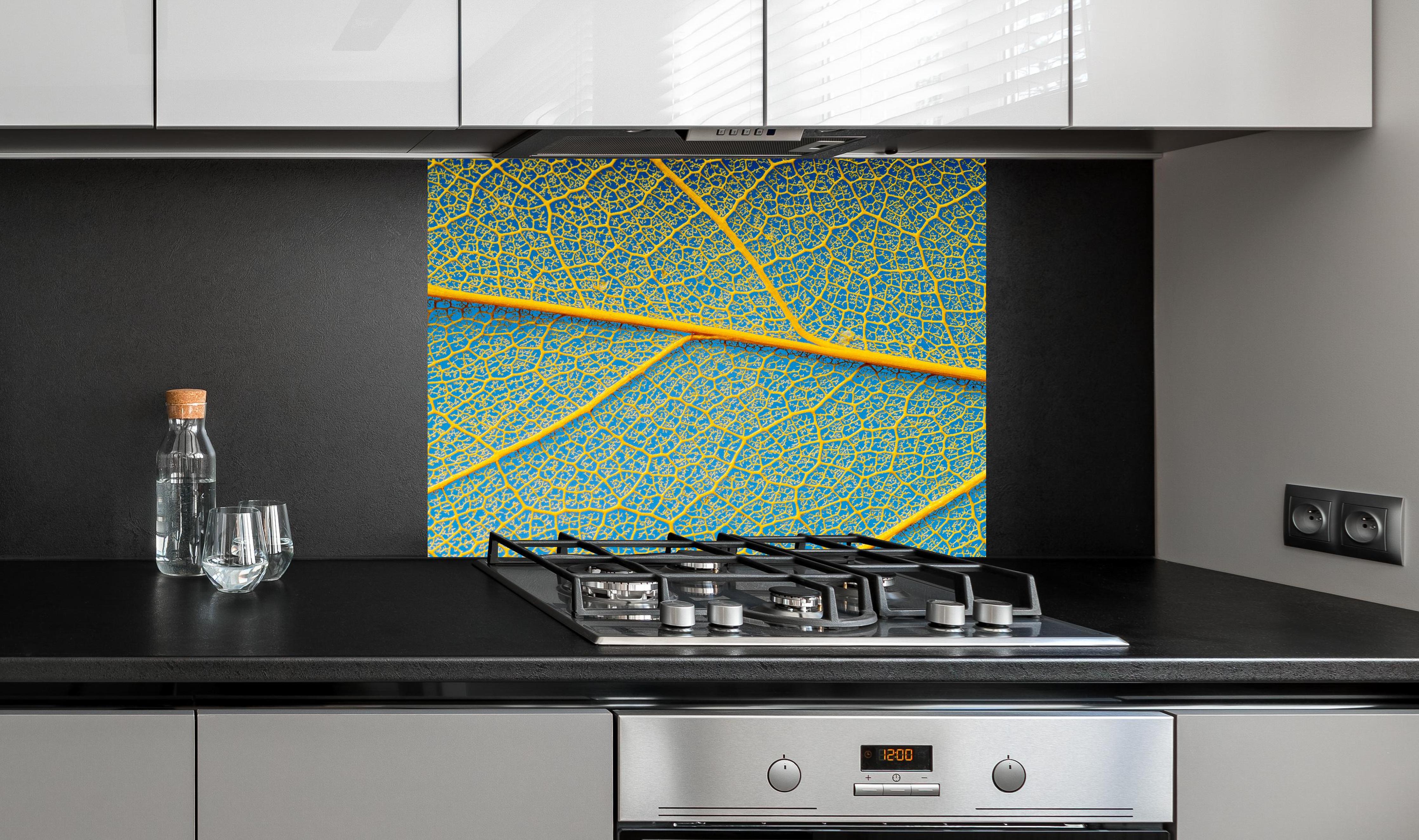 Spritzschutz - Blattstruktur in Makroaufnahme Gelb-Blau hinter einem Cerankochfeld zwischen Holz-Kochutensilien
