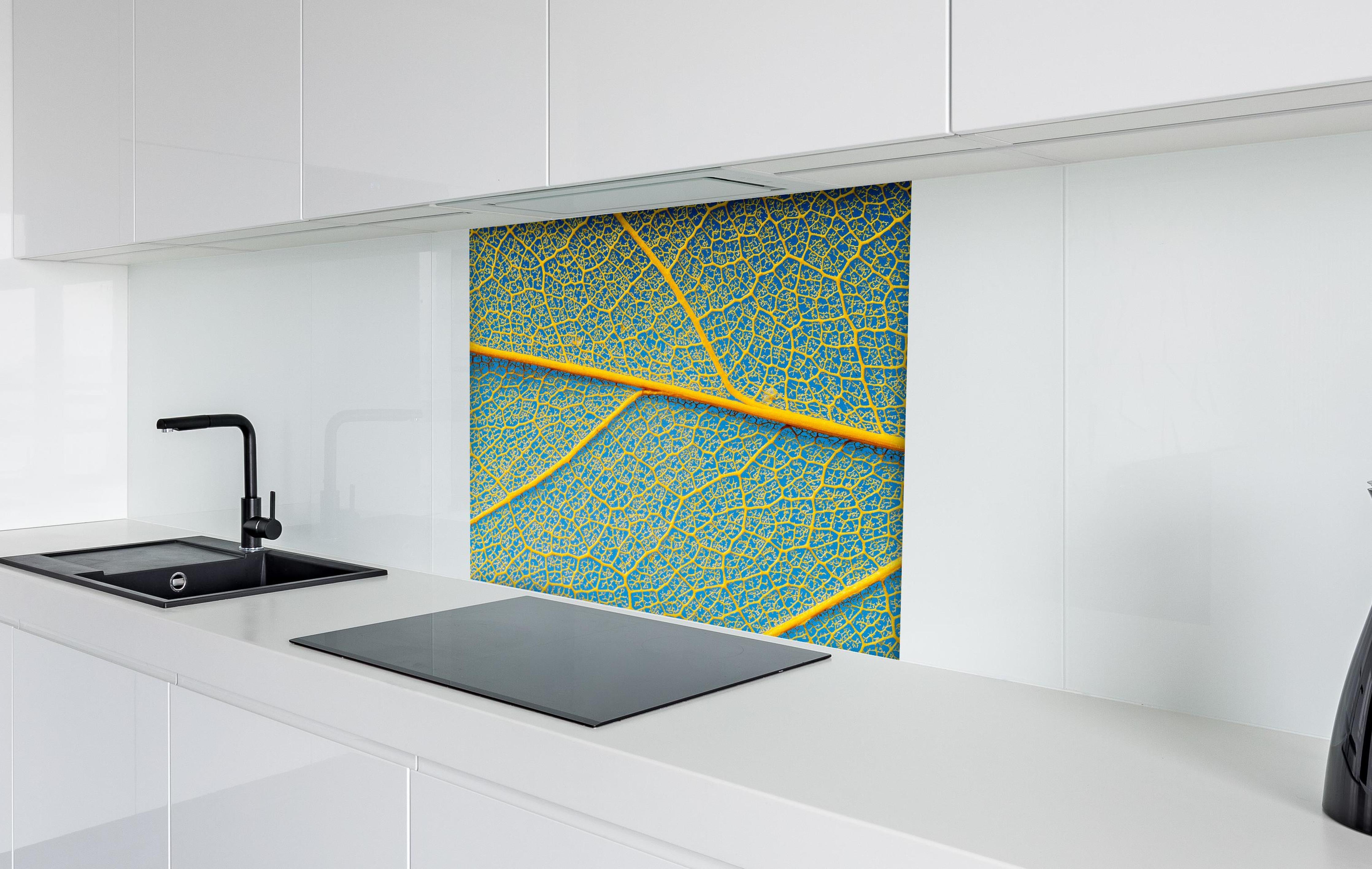 Spritzschutz - Blattstruktur in Makroaufnahme Gelb-Blau hinter einem Cerankochfeld zwischen Holz-Kochutensilien
