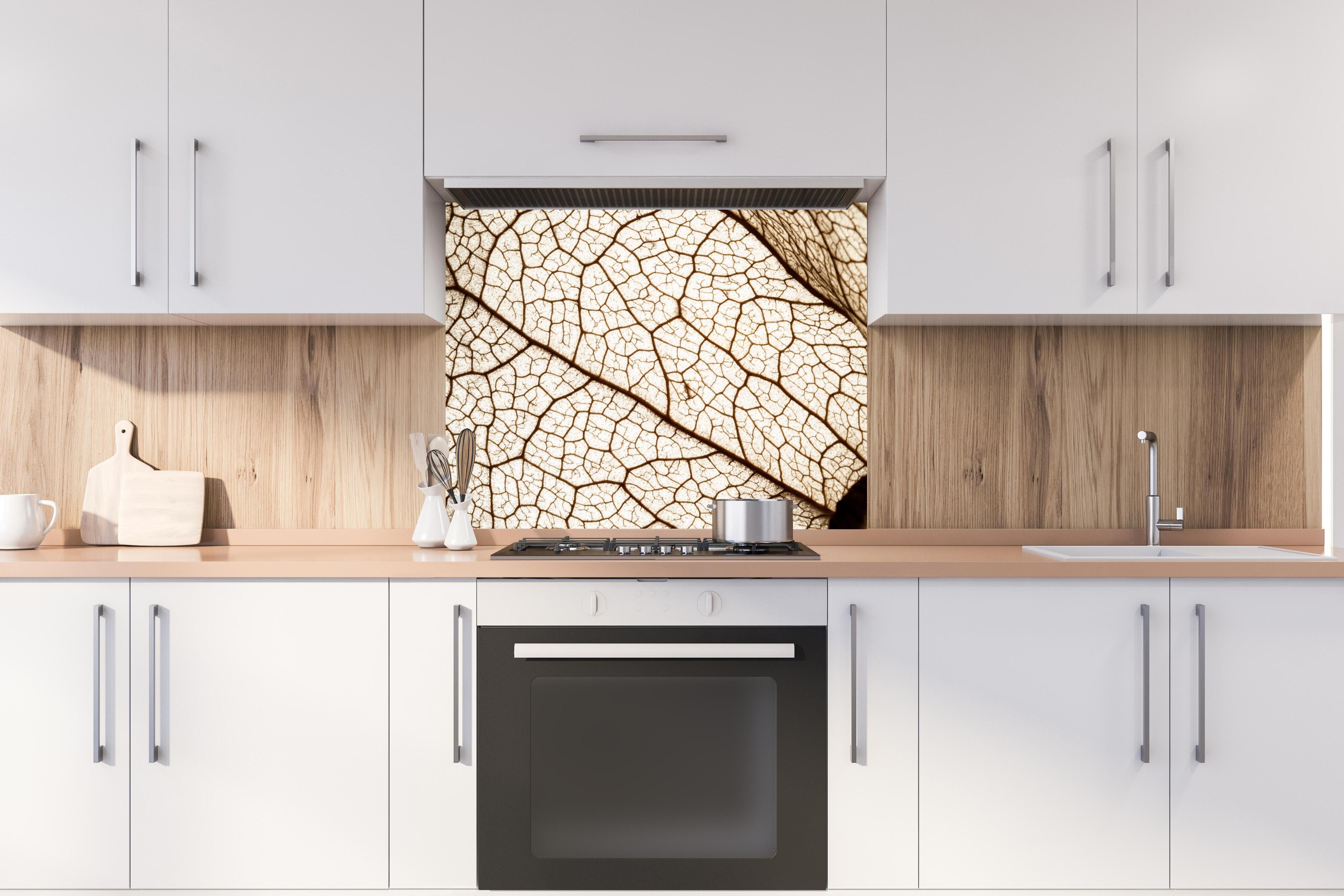 Spritzschutz - Blatttextur im Detail hinter einem Cerankochfeld zwischen Holz-Kochutensilien

